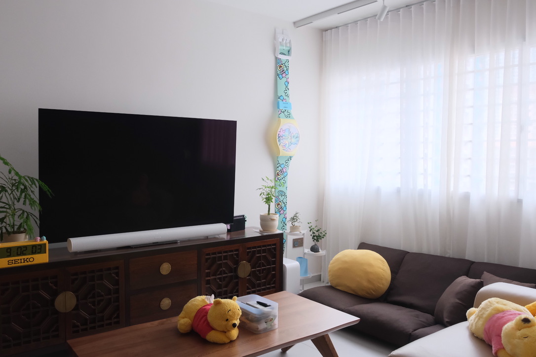 What we've learnt about hosting - Large black TV, white wall, wooden cabinet, potted plants, yellow plush toys, Seiko clock