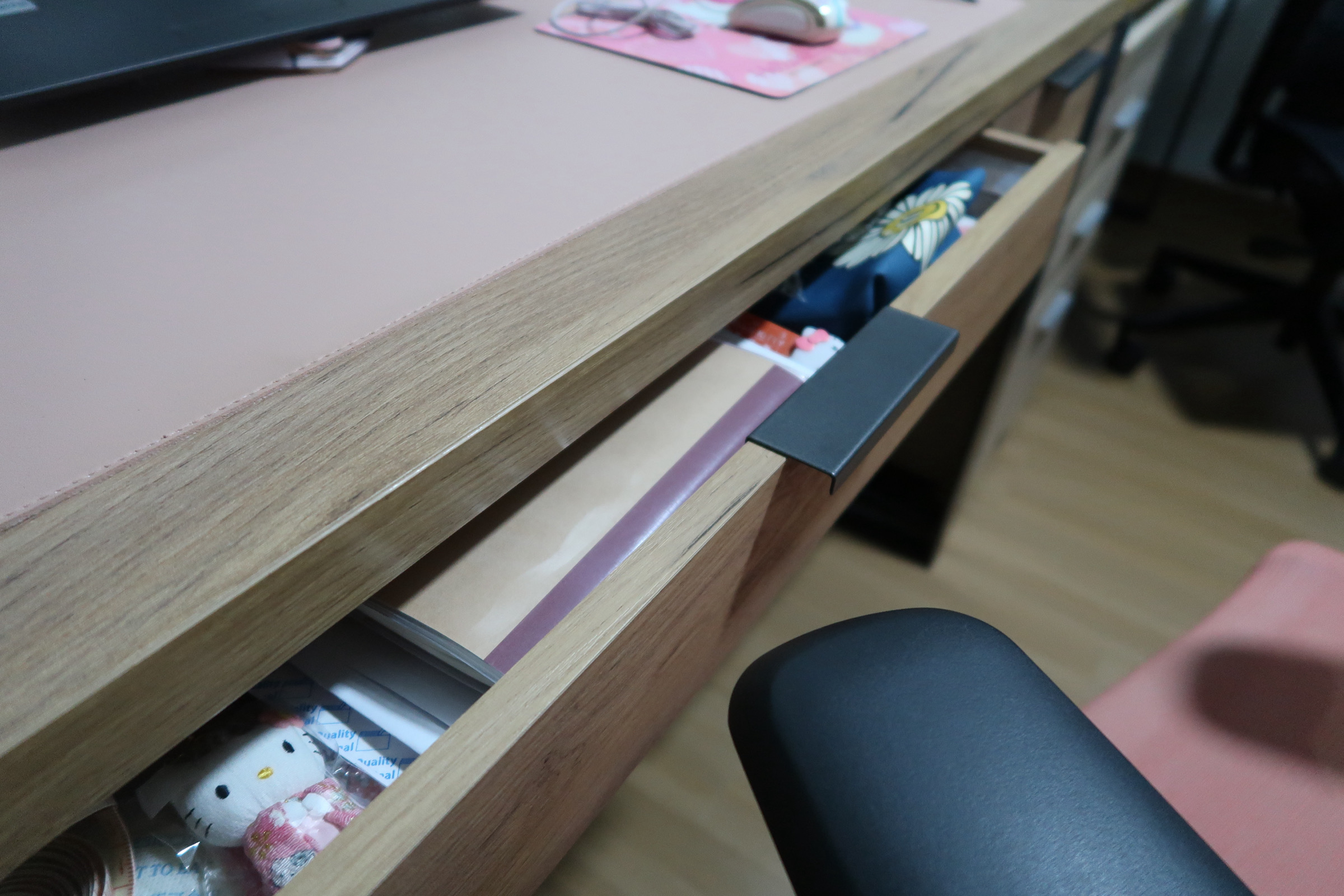 Our work space customised to our needs  - Wooden desk drawer, Hello Kitty plush toy, pink desk mat, black office chair, desk