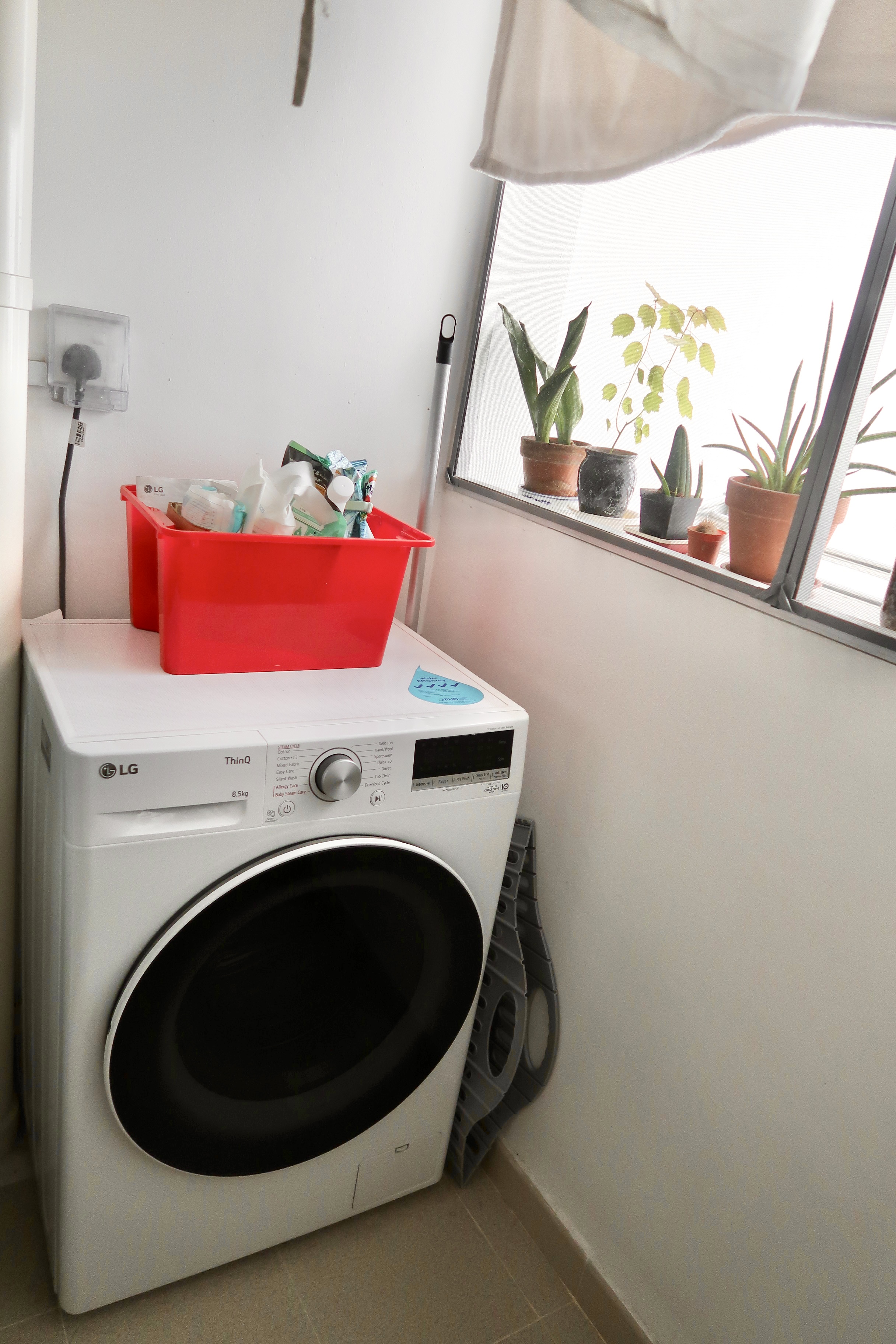 Multi-Use Service Yard with a Fermentation Nook  - White LG washing machine, red plastic bin, potted plants on windowsill