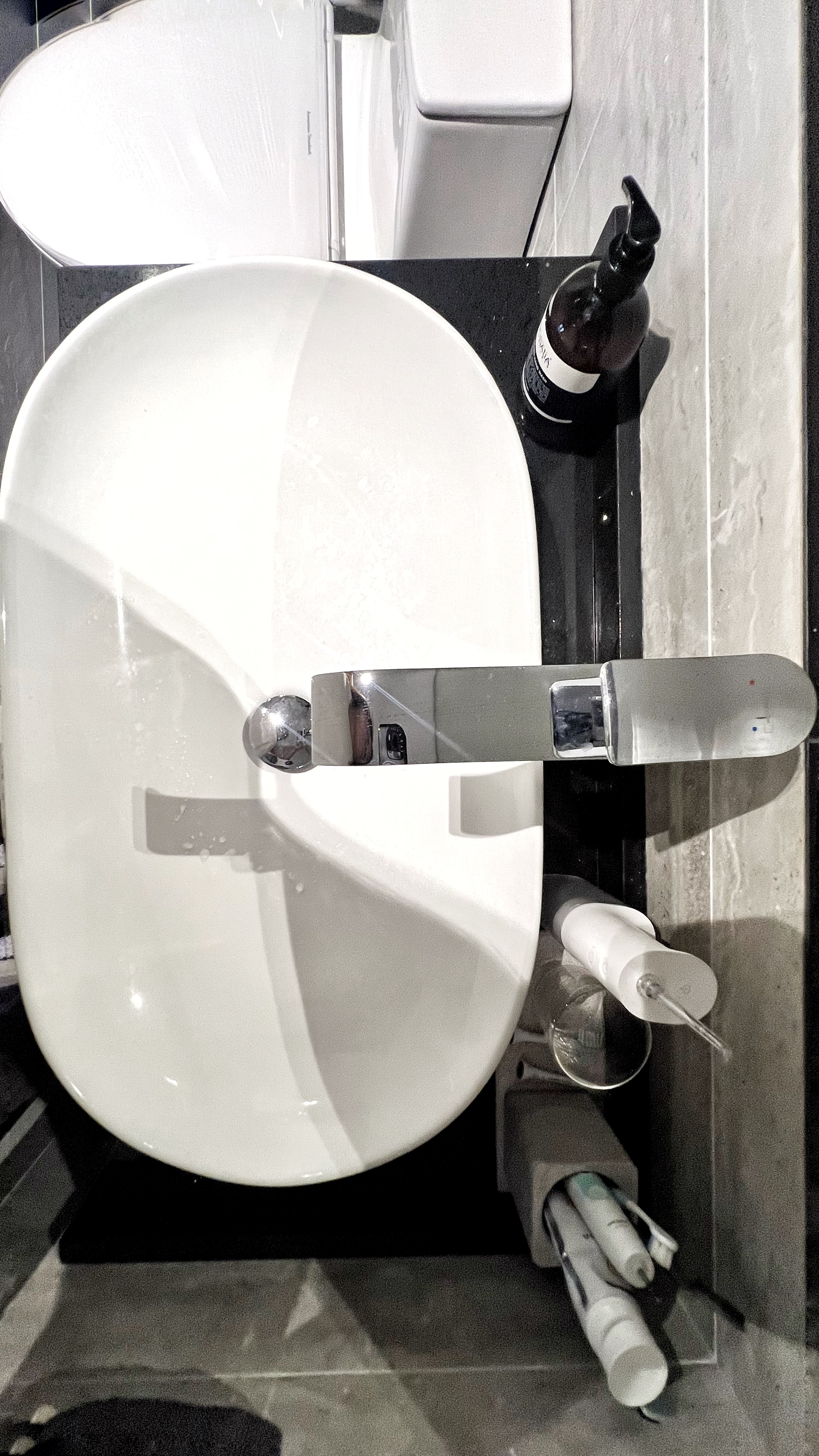 From Routine to Retreat: Crafting a Luxurious Bathroom Experience - White oval-shaped sink, black countertop, modern bathroom