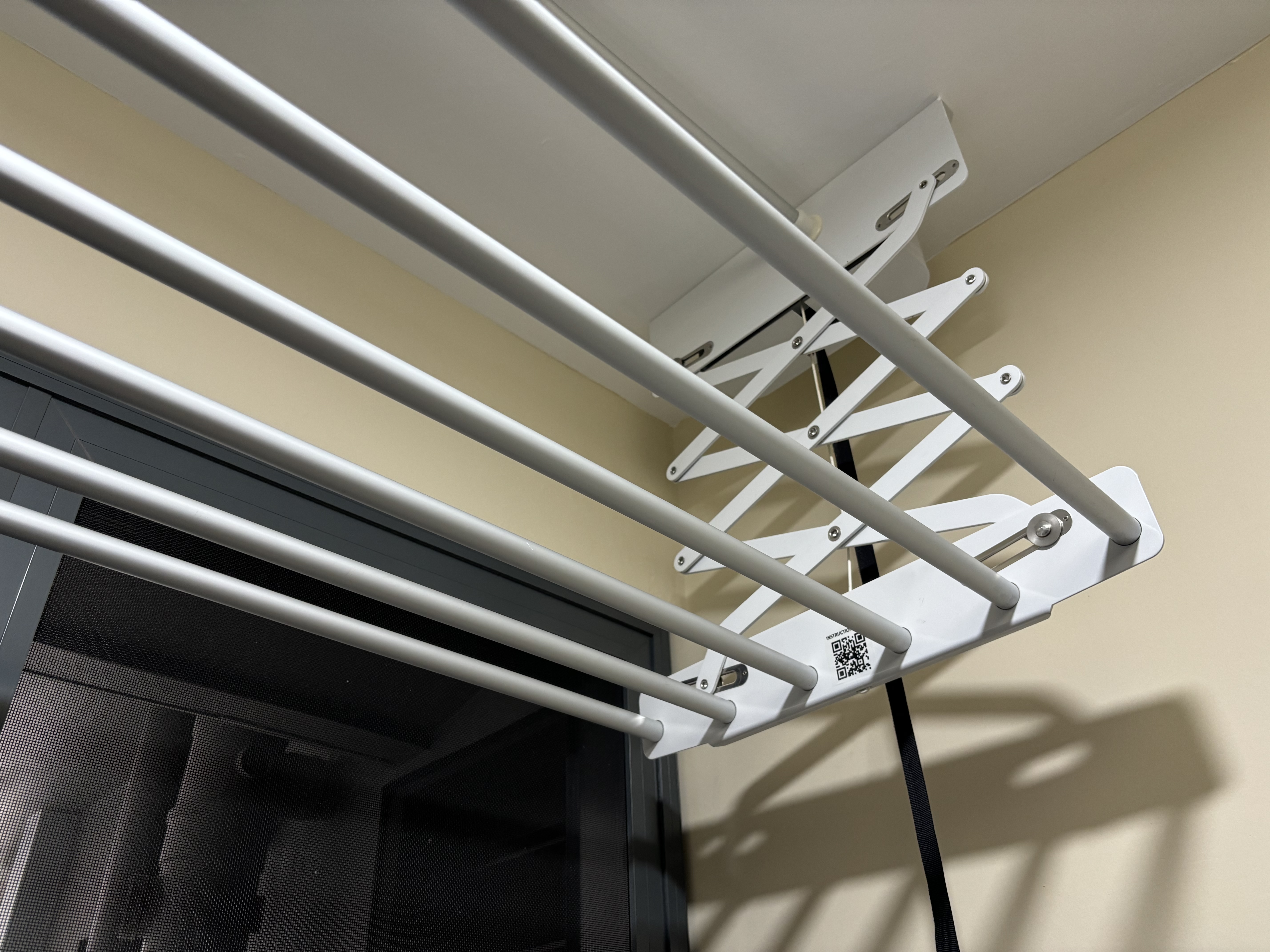 BTO Laundry Rack: To keep or not to keep? - White metal rack, beige wall, black mesh, ceiling, shadow, geometric design