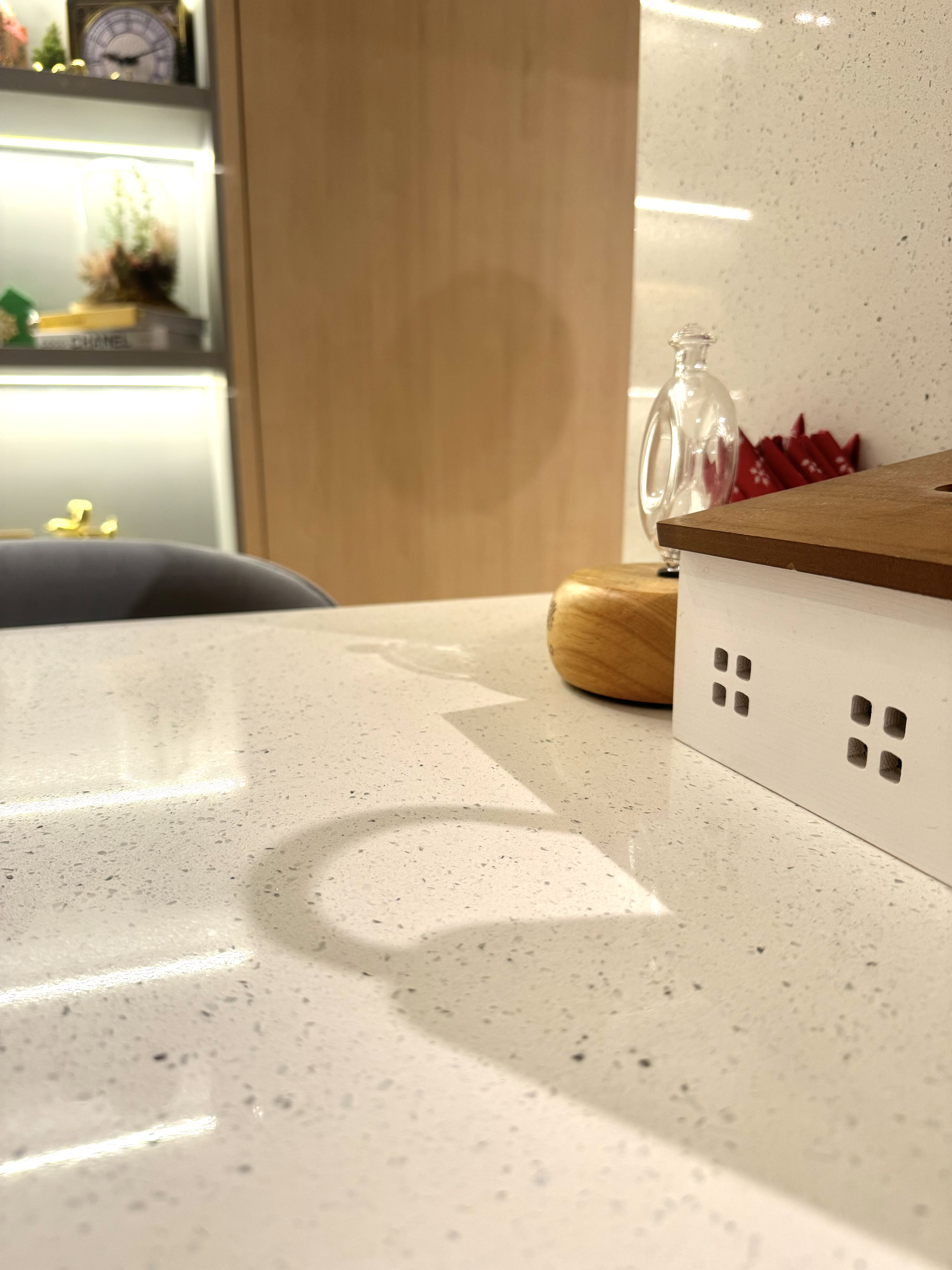 Beneath the Surfaces: Upkeep & Maintenance - White speckled countertop, modern kitchen, wooden shelf, decorative clock, small