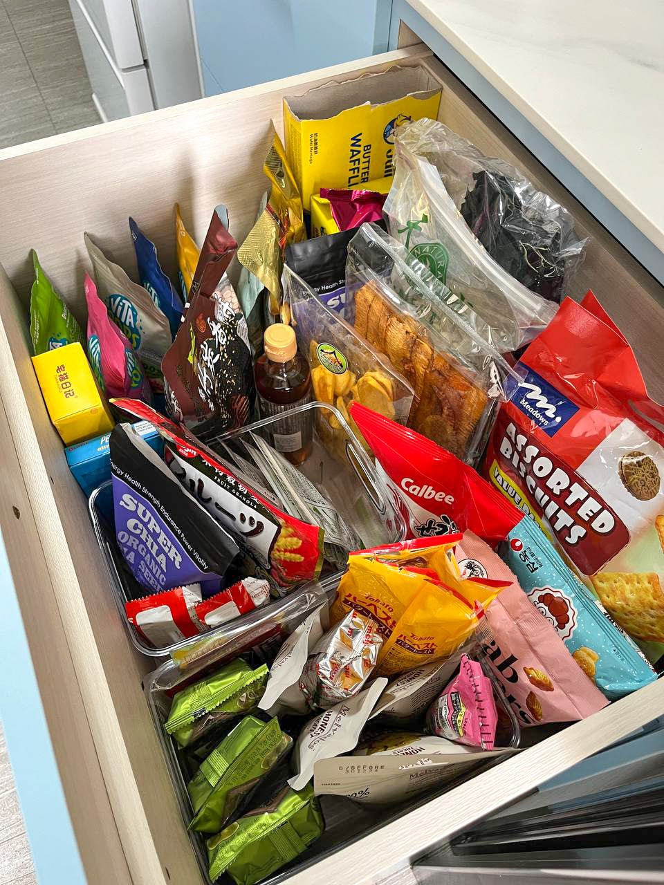 A peep into our kitchen cabinets!  - Organized snack drawer, assorted snacks, diverse packaged treats, colorful packaging