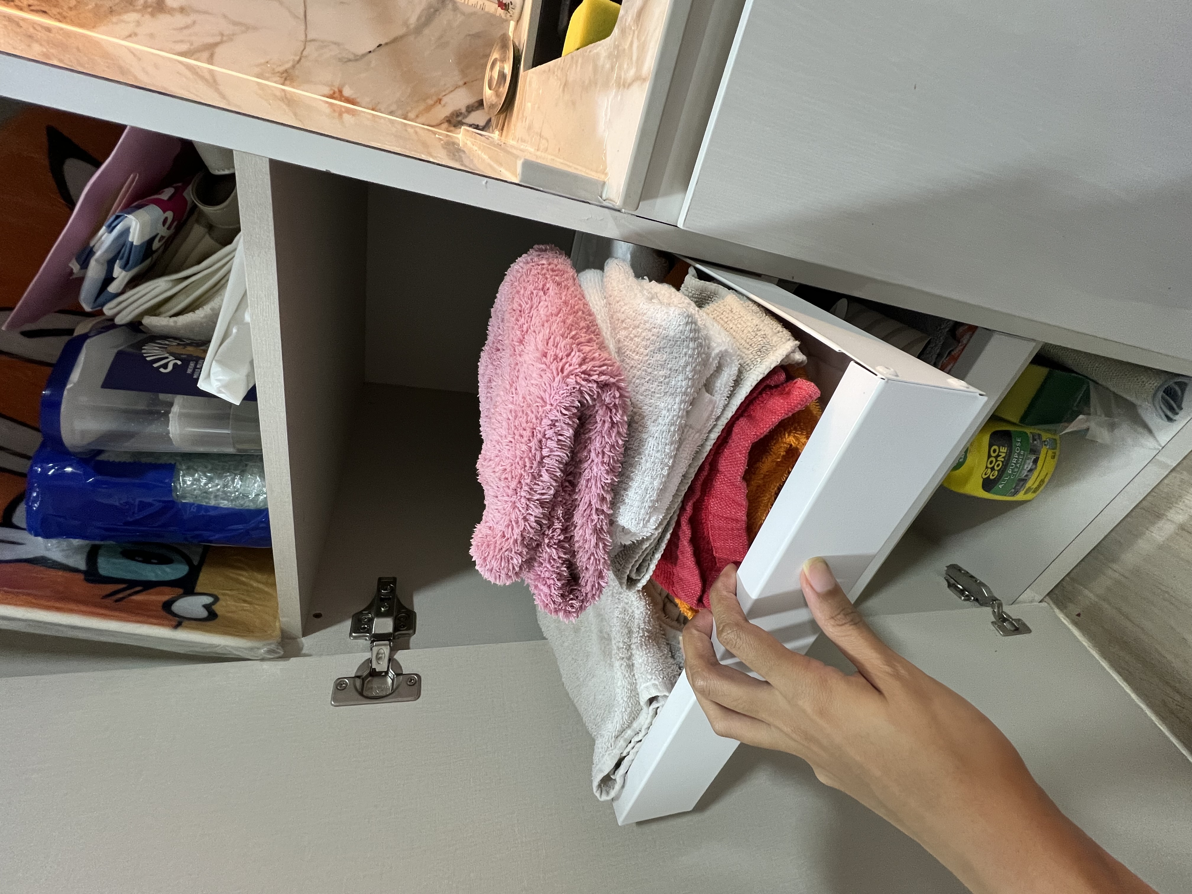 Tricks to free up counter space  - Folded towels, neatly organized, drawer, white cabinet, household items, laundry