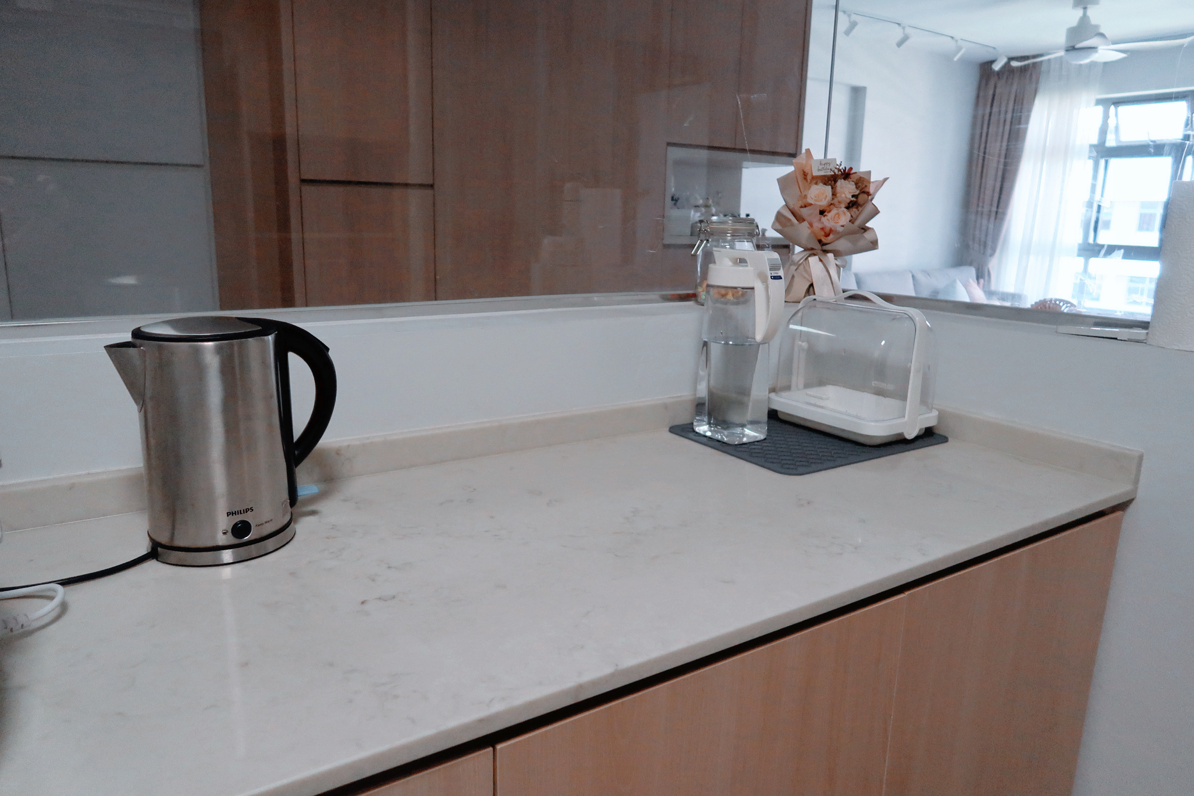 Our Enclosed Kitchen Organisation With Plenty Storage  - Silver Philips electric kettle, white marble countertop, wooden