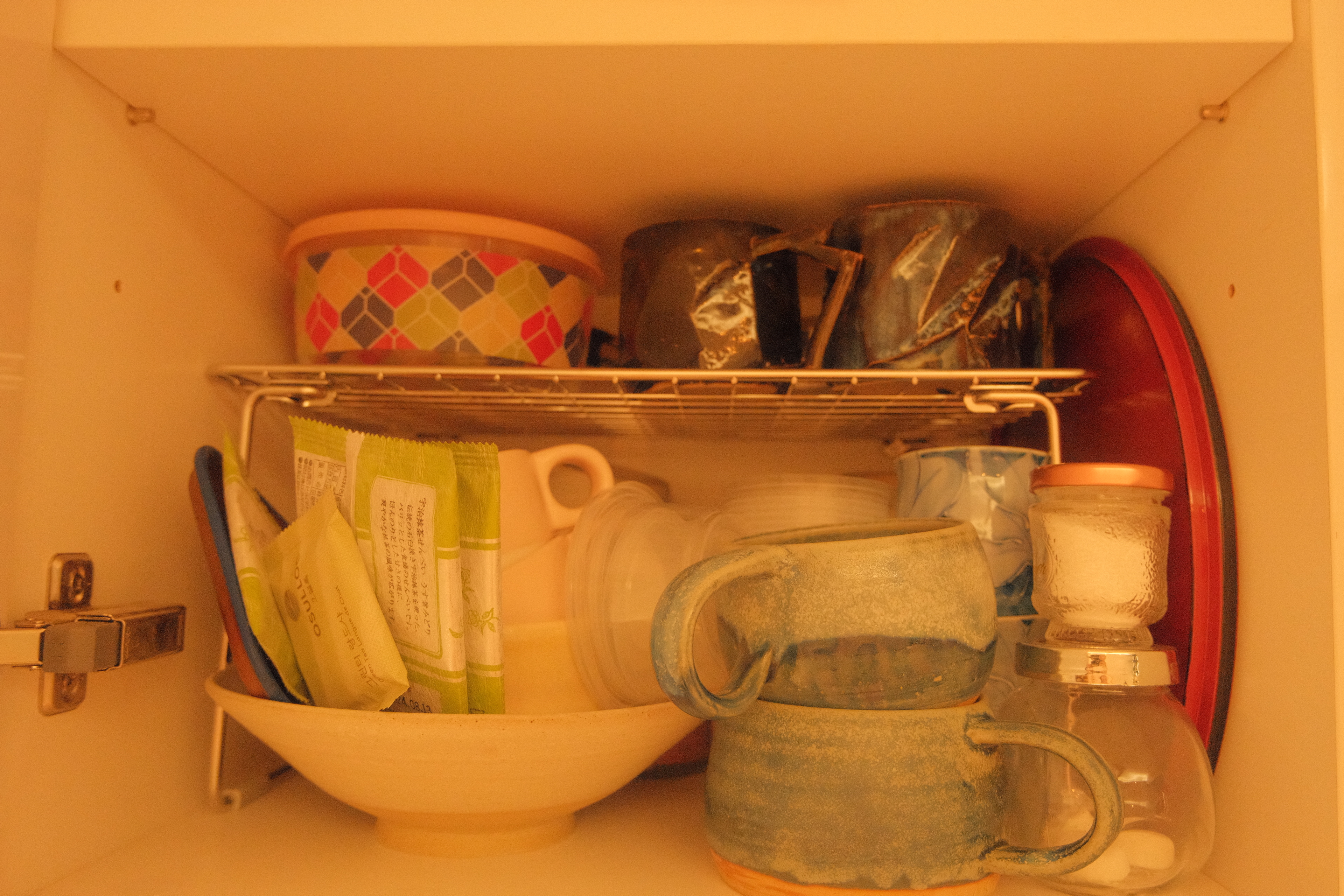 Check out how I Marie Kondo-ed my Kitchen  - muted kitchen cabinet, colorful bowls, ceramic mugs, green and white packets
