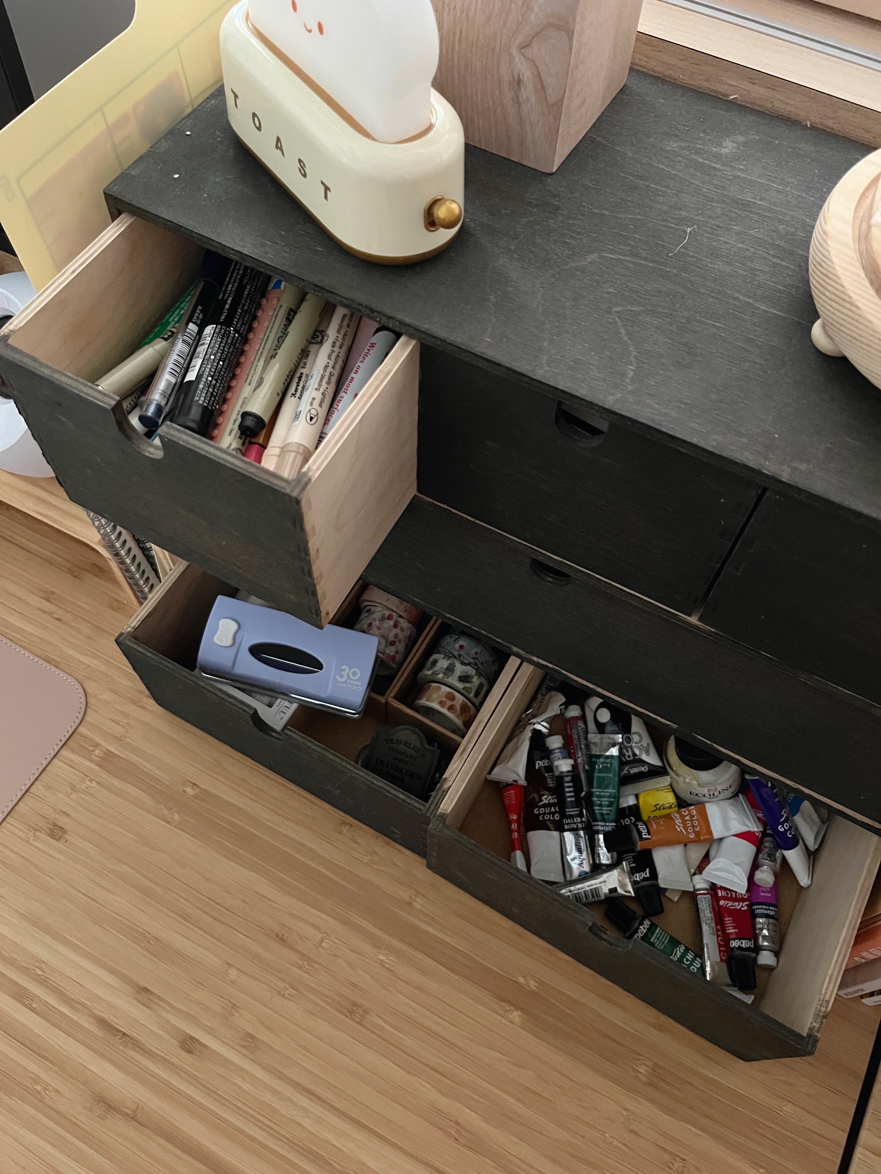 How I organise my desk  - Toaster, wooden drawer, neatly organized, stationery items, pens, markers, paint tubes, travel