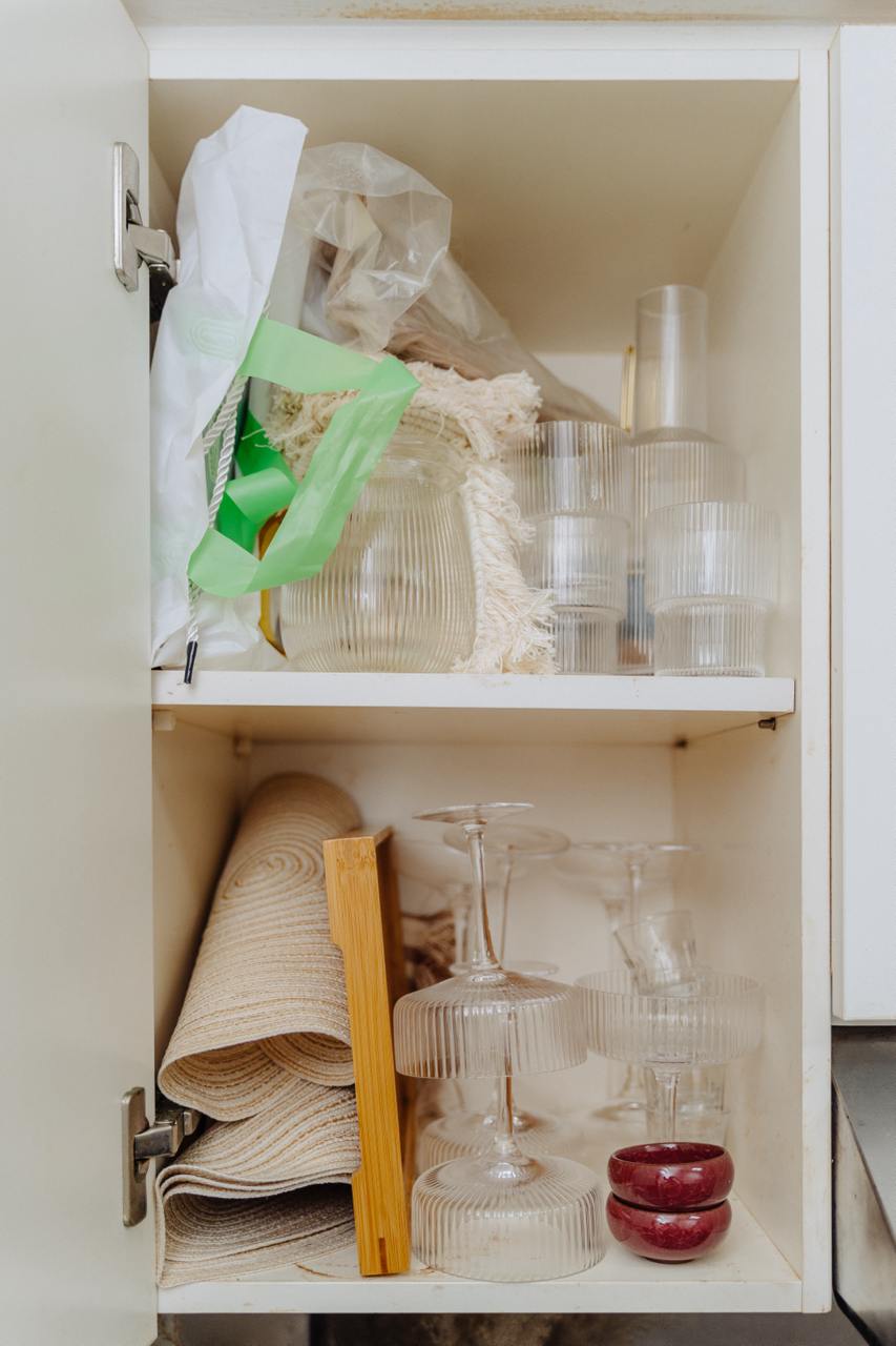Tiny Kitchen Living: Organisation Tips To Live Mess Free - Clear glassware, stacked wine glasses, decorative plates, woven