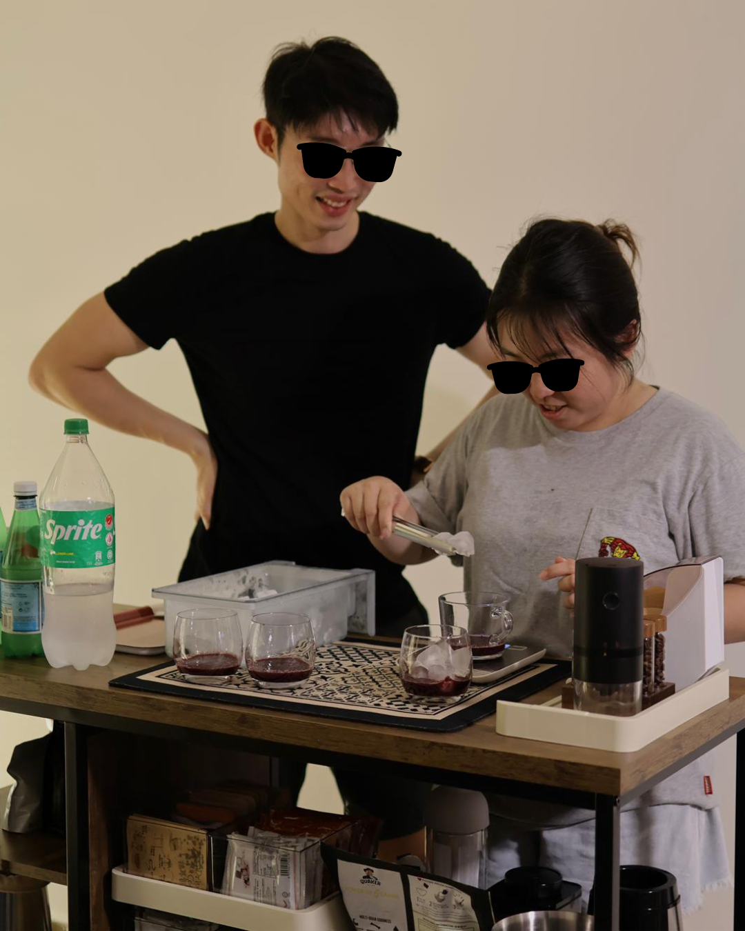 Hosting at Home: From 2 to 22  - Two people wearing sunglasses, standing behind a table with drinks, one pouring liquid into