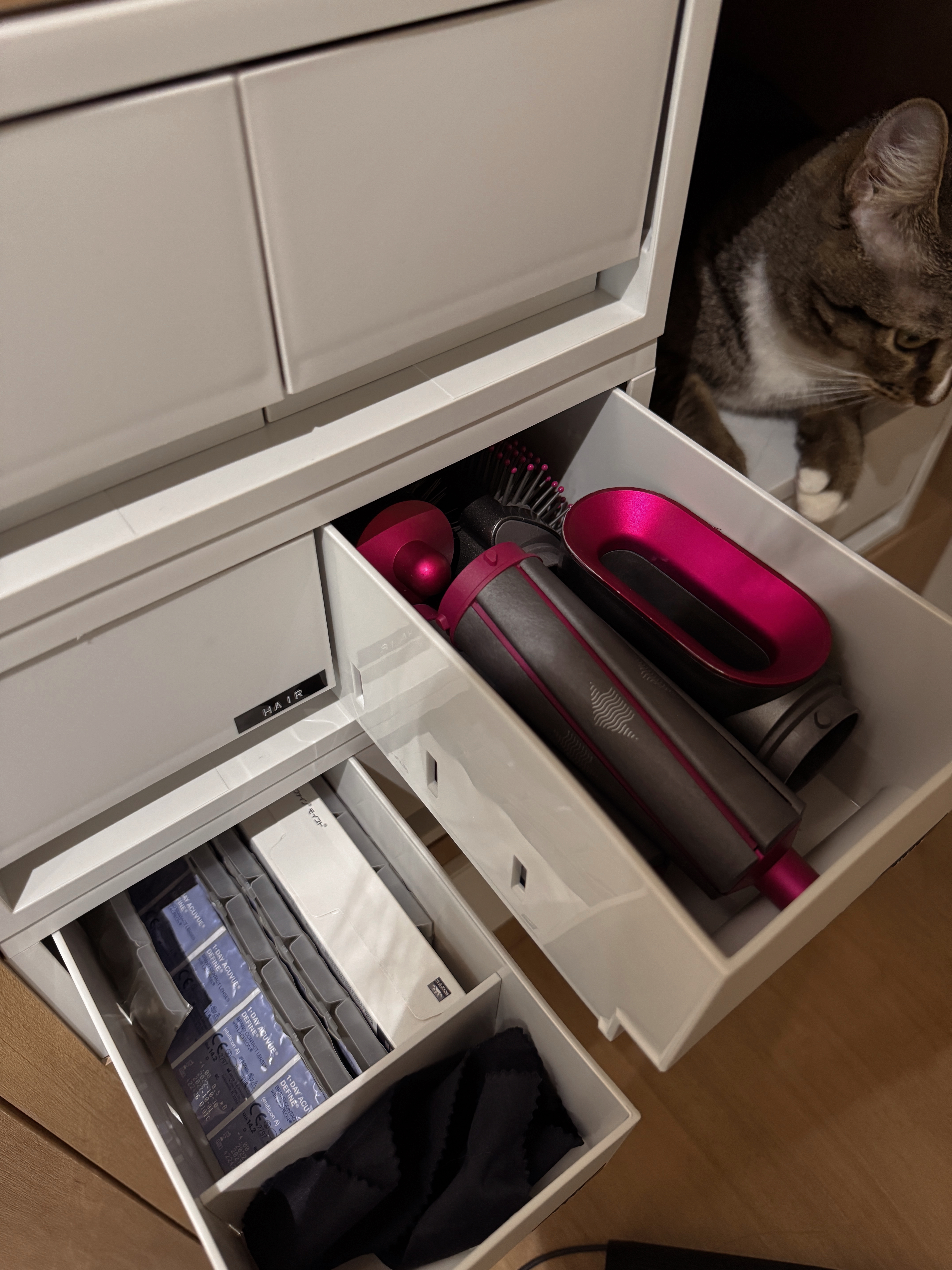 Home Organization We Love - White drawer, cat peeking, hair dryer, pink hair dryer, black hairbrush, white hair dryer, gray