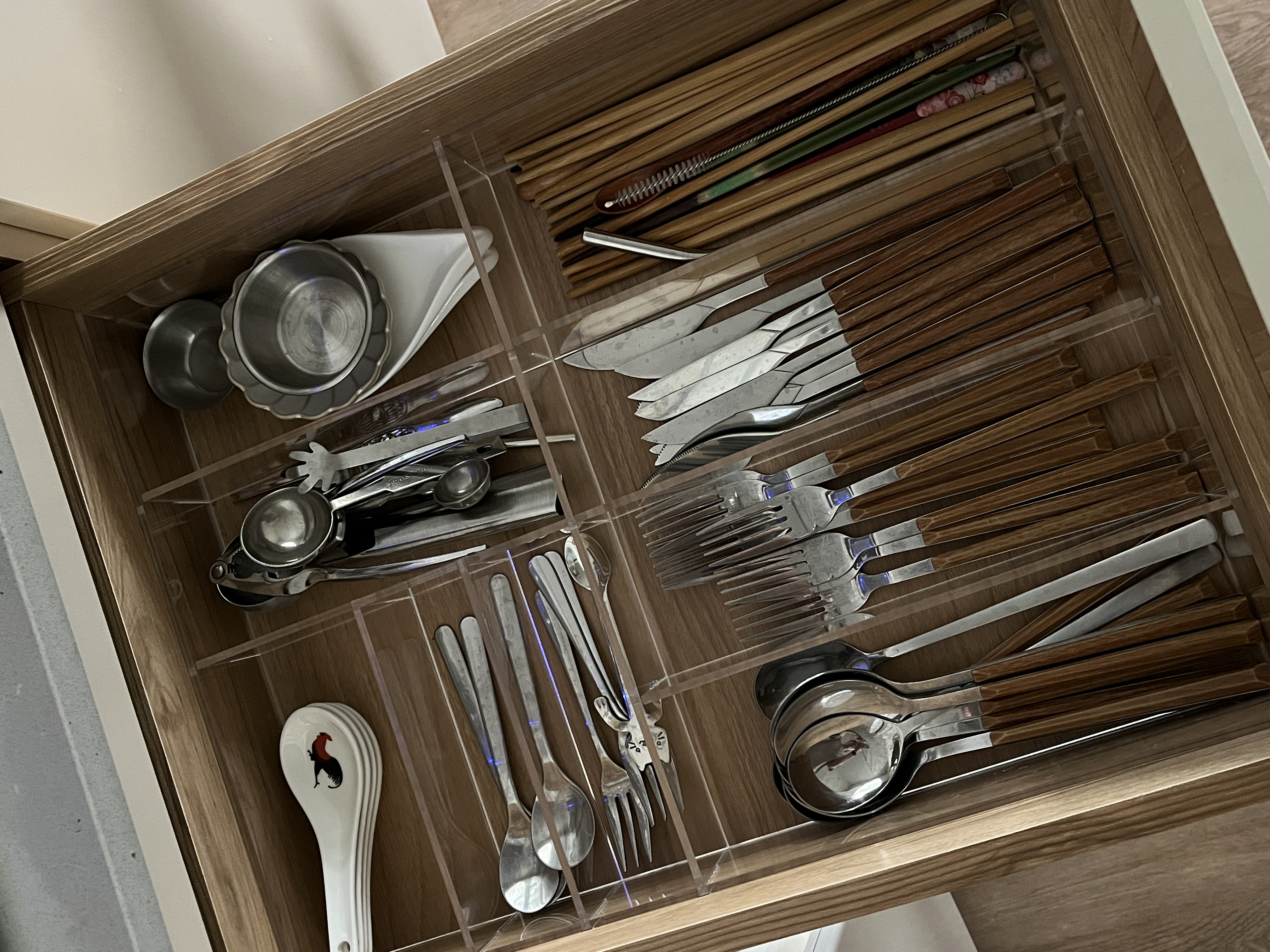 Home Organization We Love - Clear glass drawer, neatly organized utensils, wooden interior, stainless steel tools, plastic
