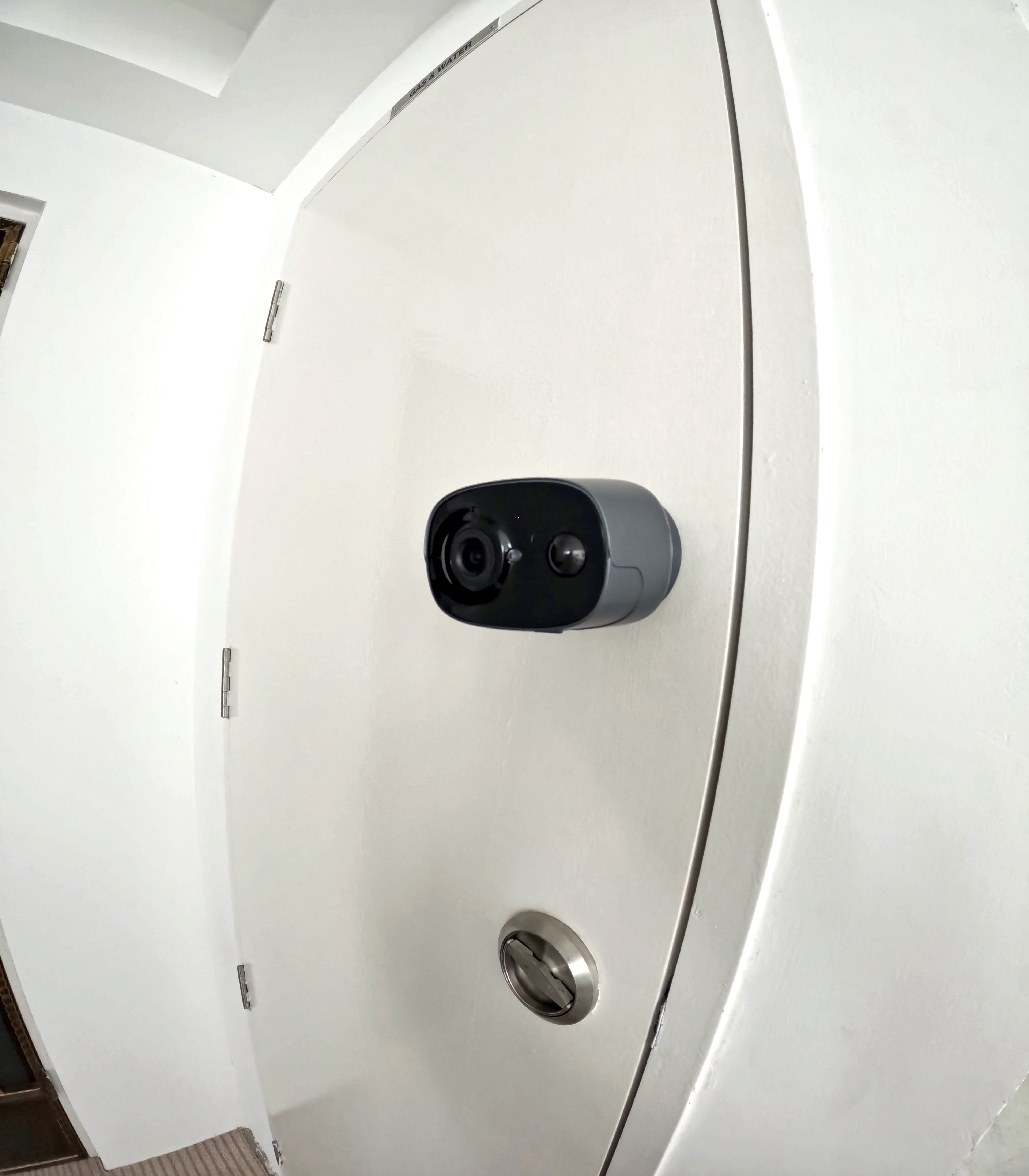 Urban Oasis: A Plant-Filled Corridor with a Bicycle Rack 🌿🚲 - White door, black security camera, metal hinge, white wall