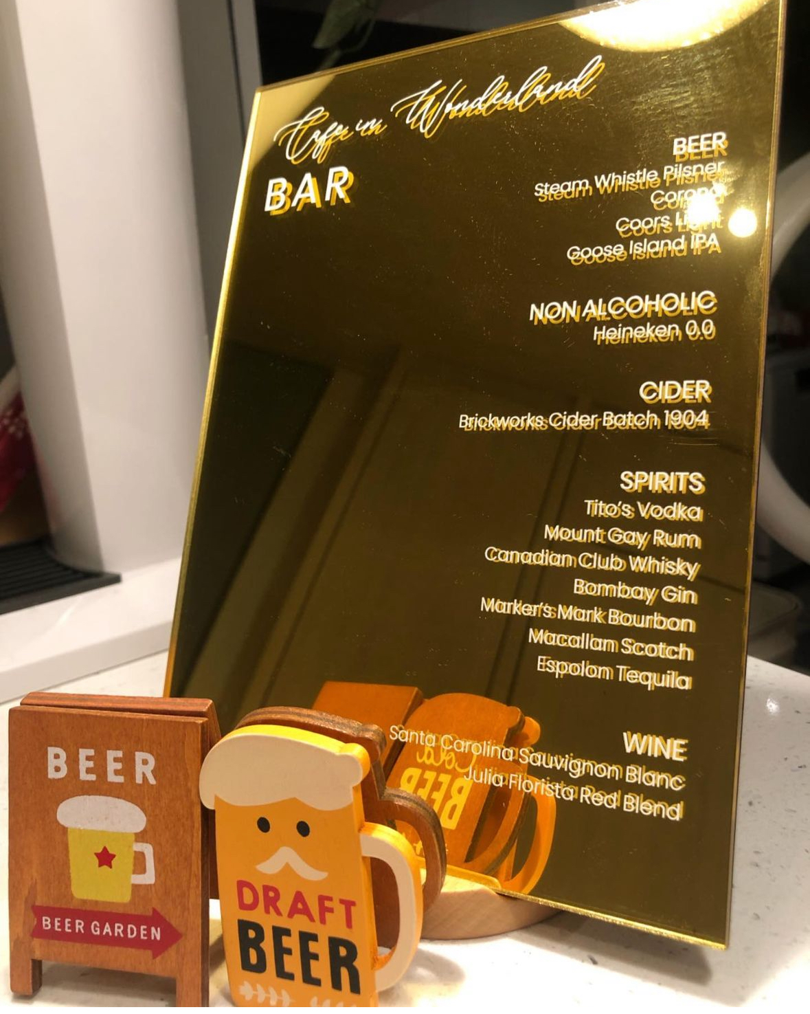FAQ: Your Space = Your Vibes 🏠  - Golden bar display featuring a list of beverages, including non-alcoholic options, cider