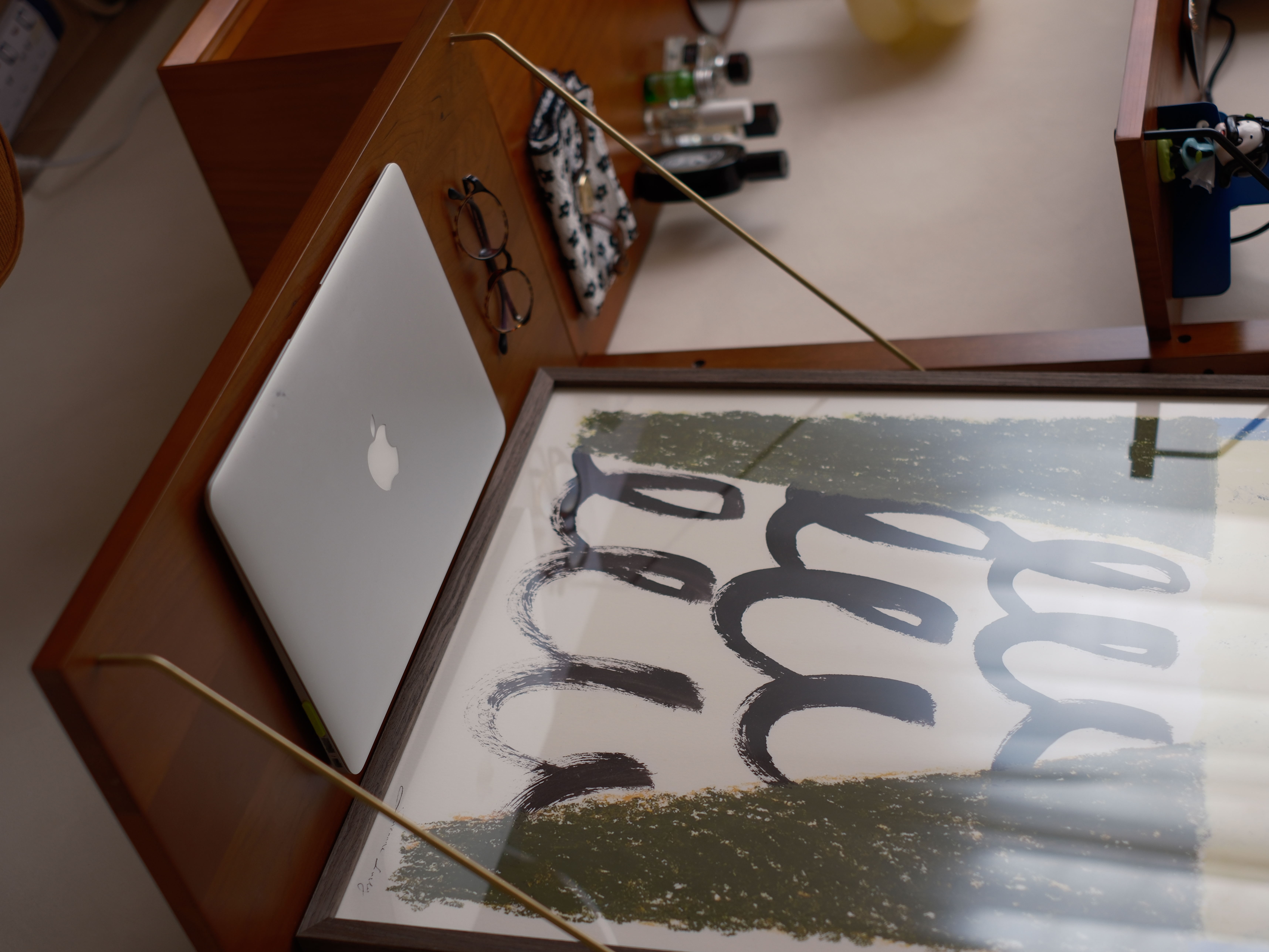 Blending Wardrobe and Study in One Space - Silver laptop with Apple logo, wooden desk, framed artwork, abstract design, green