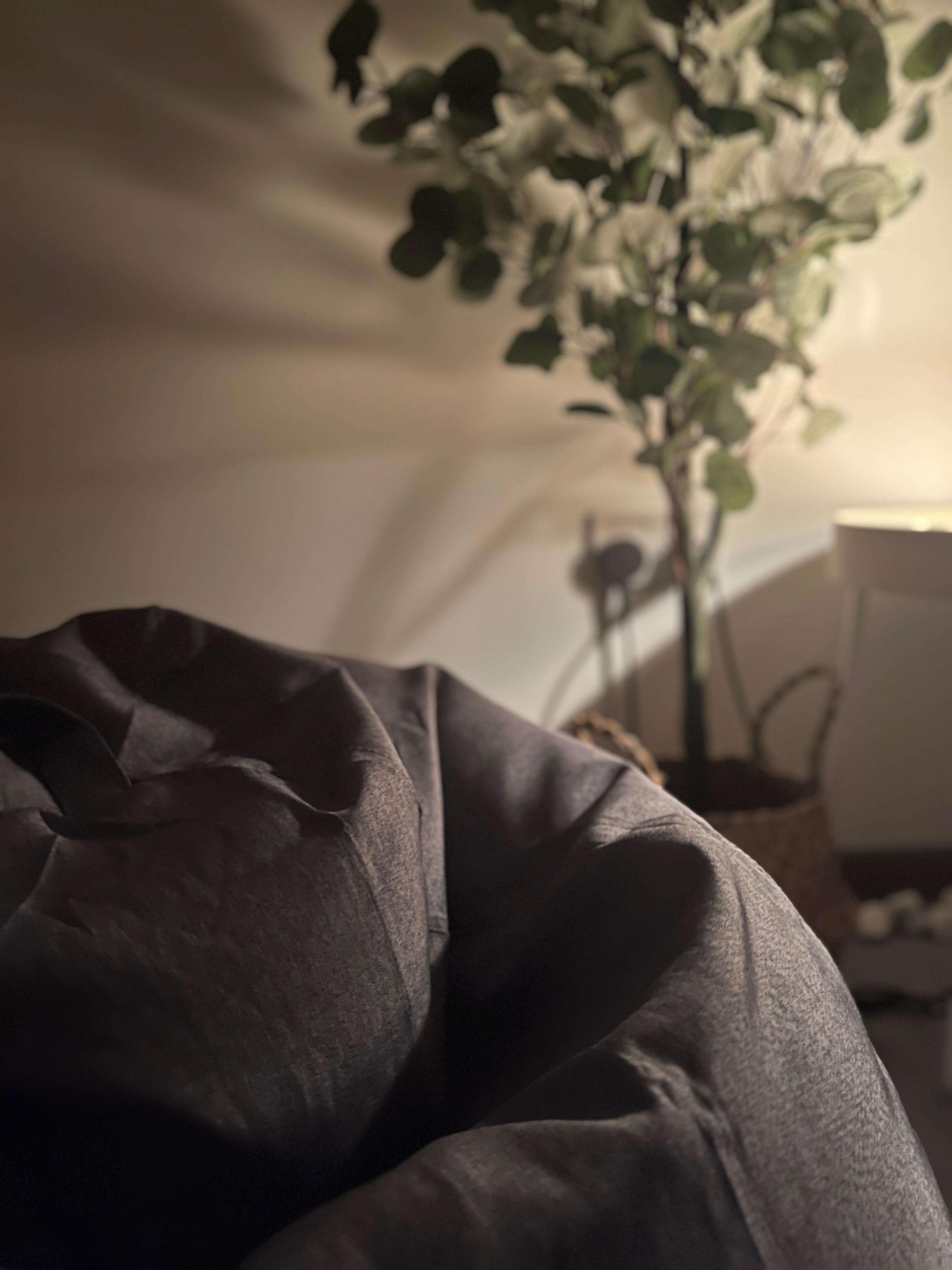 Cozy corner for a warm cup of tea and a good book  - Soft, dark fabric, cozy ambiance, indoor setting, warm lighting, blurred