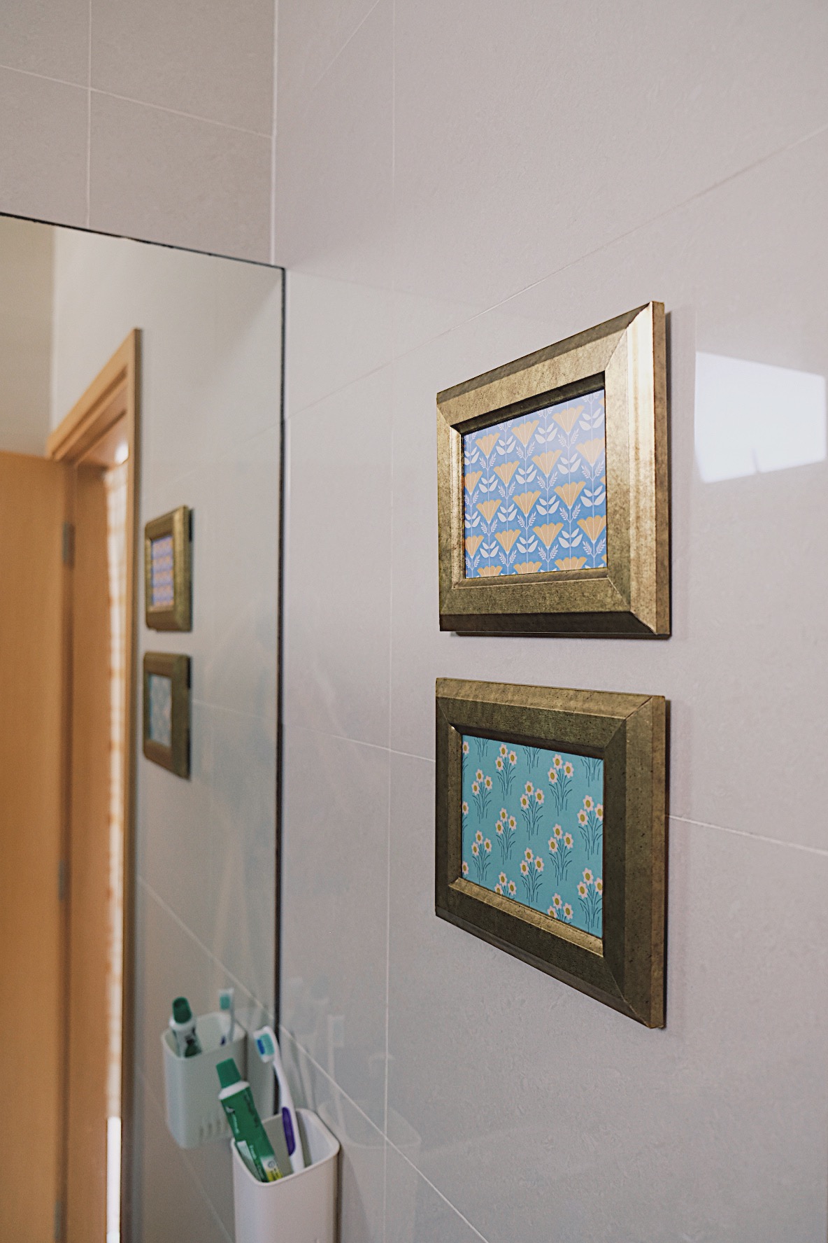 Styling our bathrooms with framed magazine cutouts - Gold-framed picture with blue and yellow floral patterns, mounted on