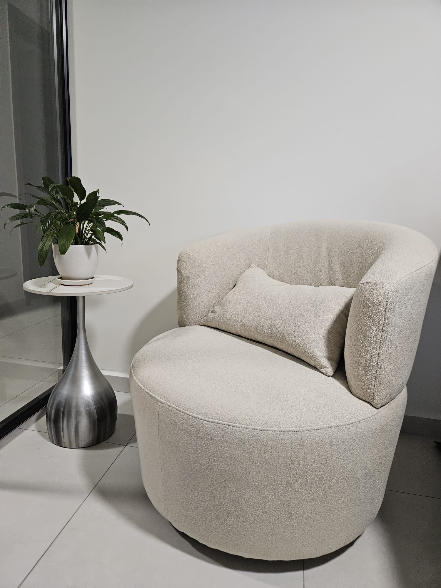 Comfy Corner - modern minimalist living room, cozy armchair, soft beige upholstery, sleek round table, indoor plant