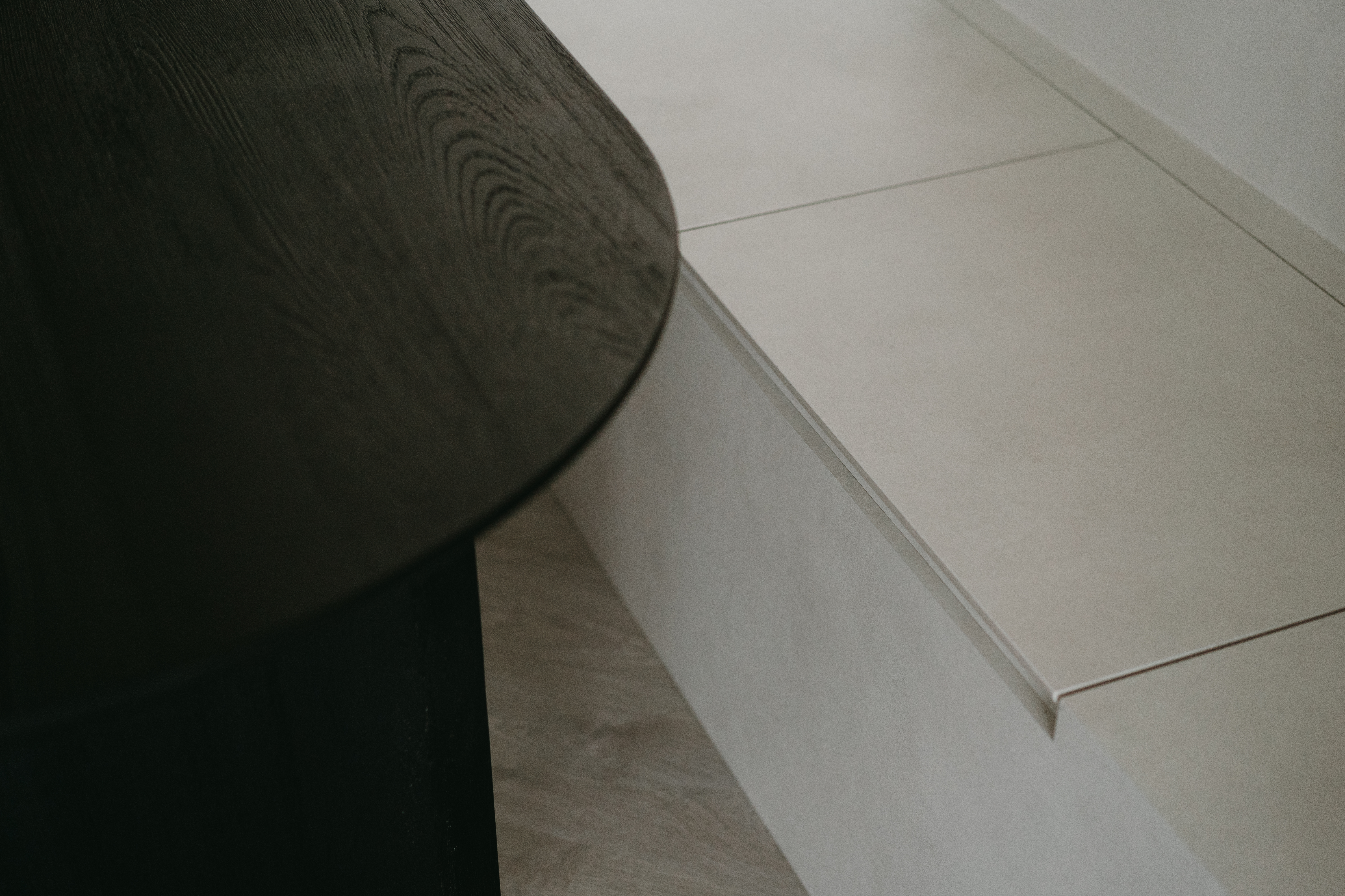 Welcome to our Grey Oasis—Minimalist vibes with sneaky storage! - Dark wooden table, light beige tiles, corner design