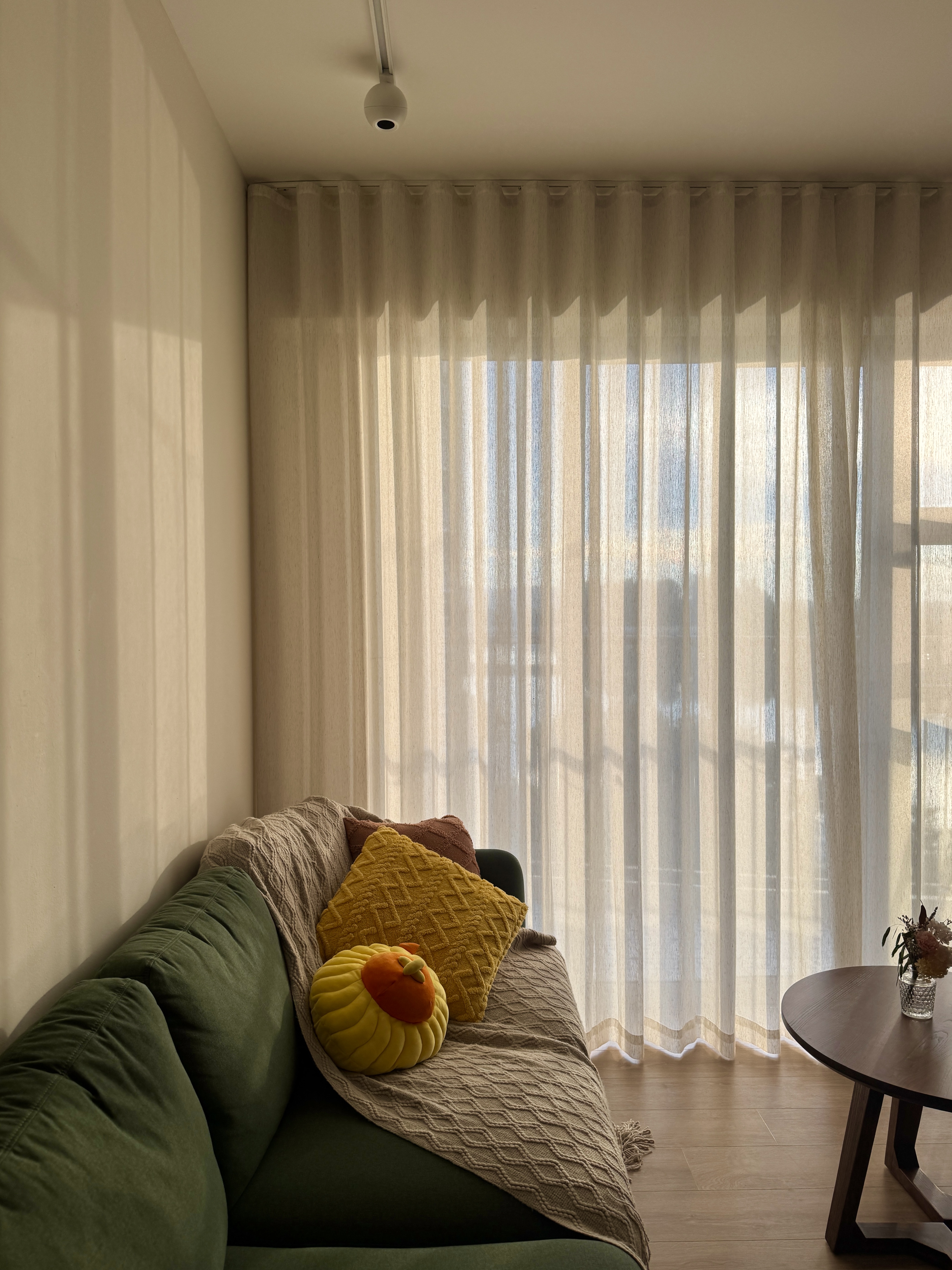 Embracing the Warmth: Our Living Room at Golden Hour  - Sunlight streaming through sheer curtains, soft shadows cast on the