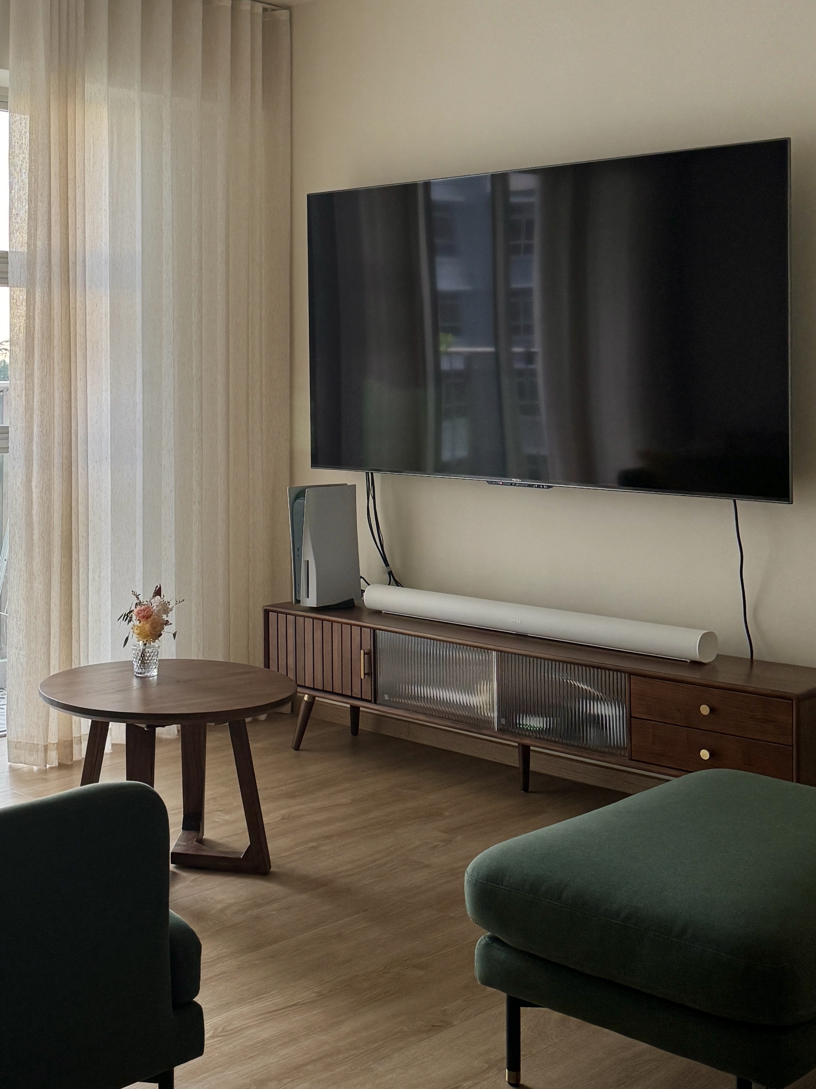 Embracing the Warmth: Our Living Room at Golden Hour  - Large flat-screen TV, minimalist decor, round wooden table, green