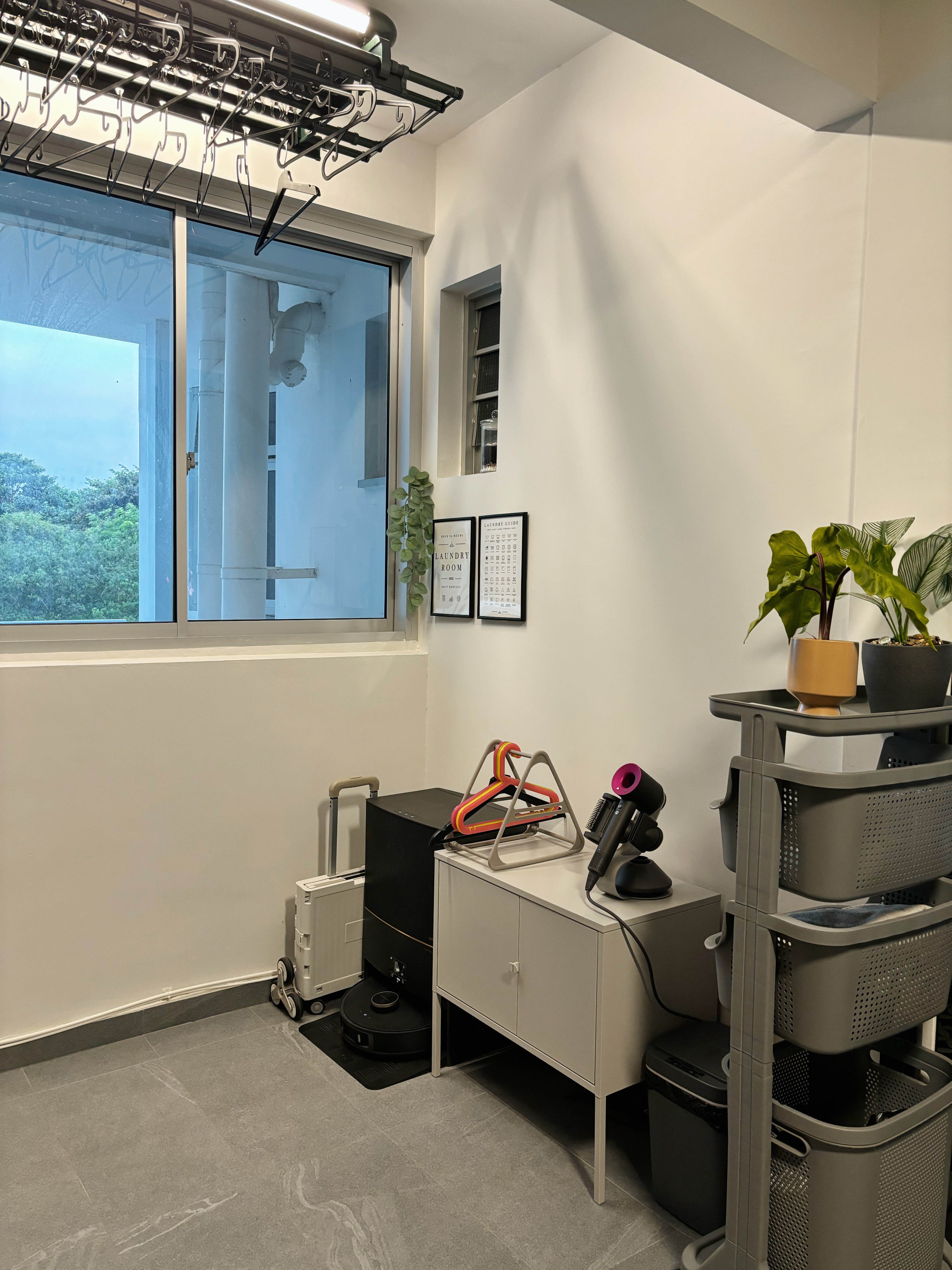 How We Made Our Service Space Work for Us - laundry room, hanging hangers, white walls, window, green plants, laundry room