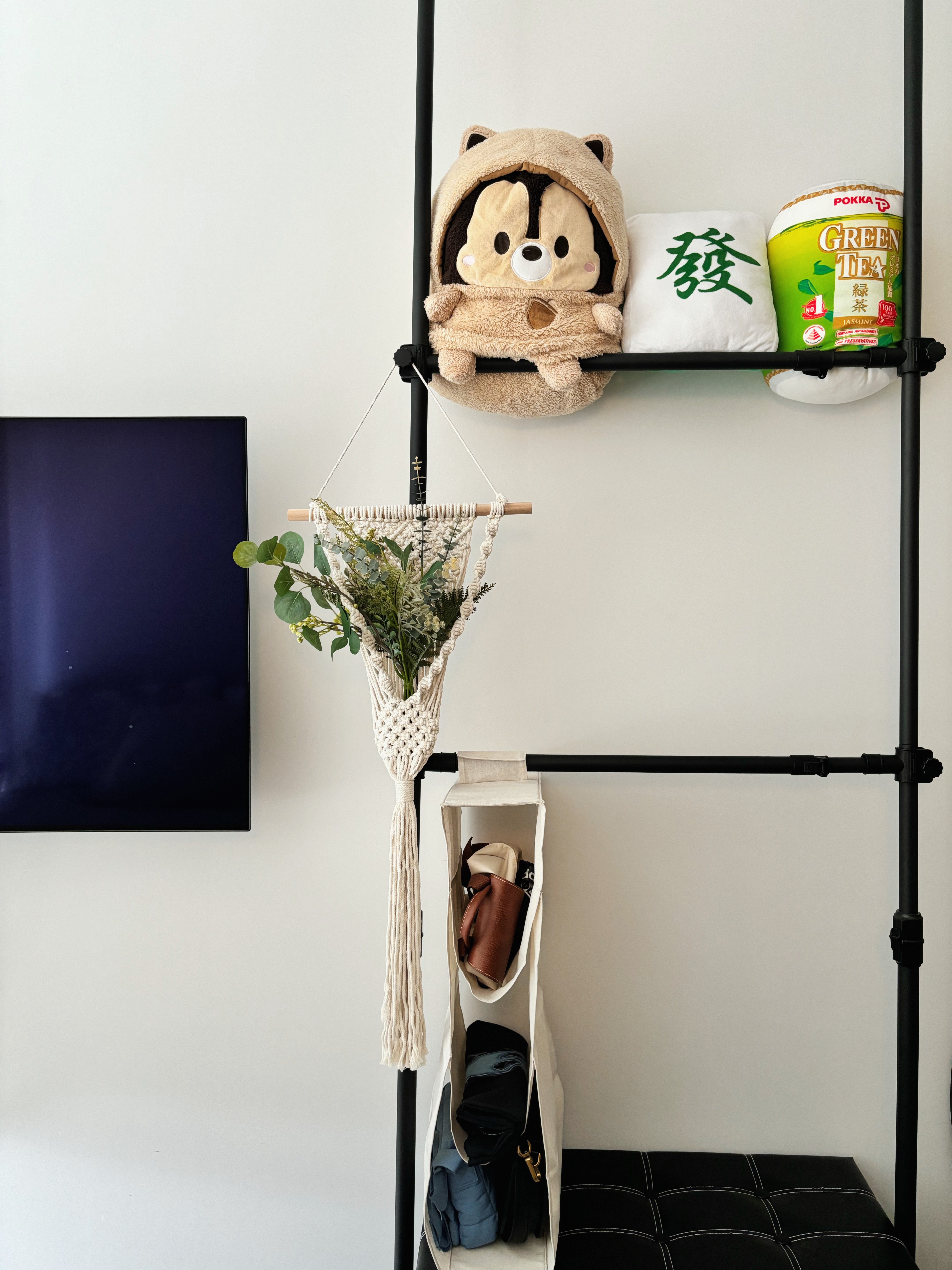 Simple Space, Big Comfort: Step Into Our Guest Room - - Black metal shelving unit with hanging basket, plush bear, and green