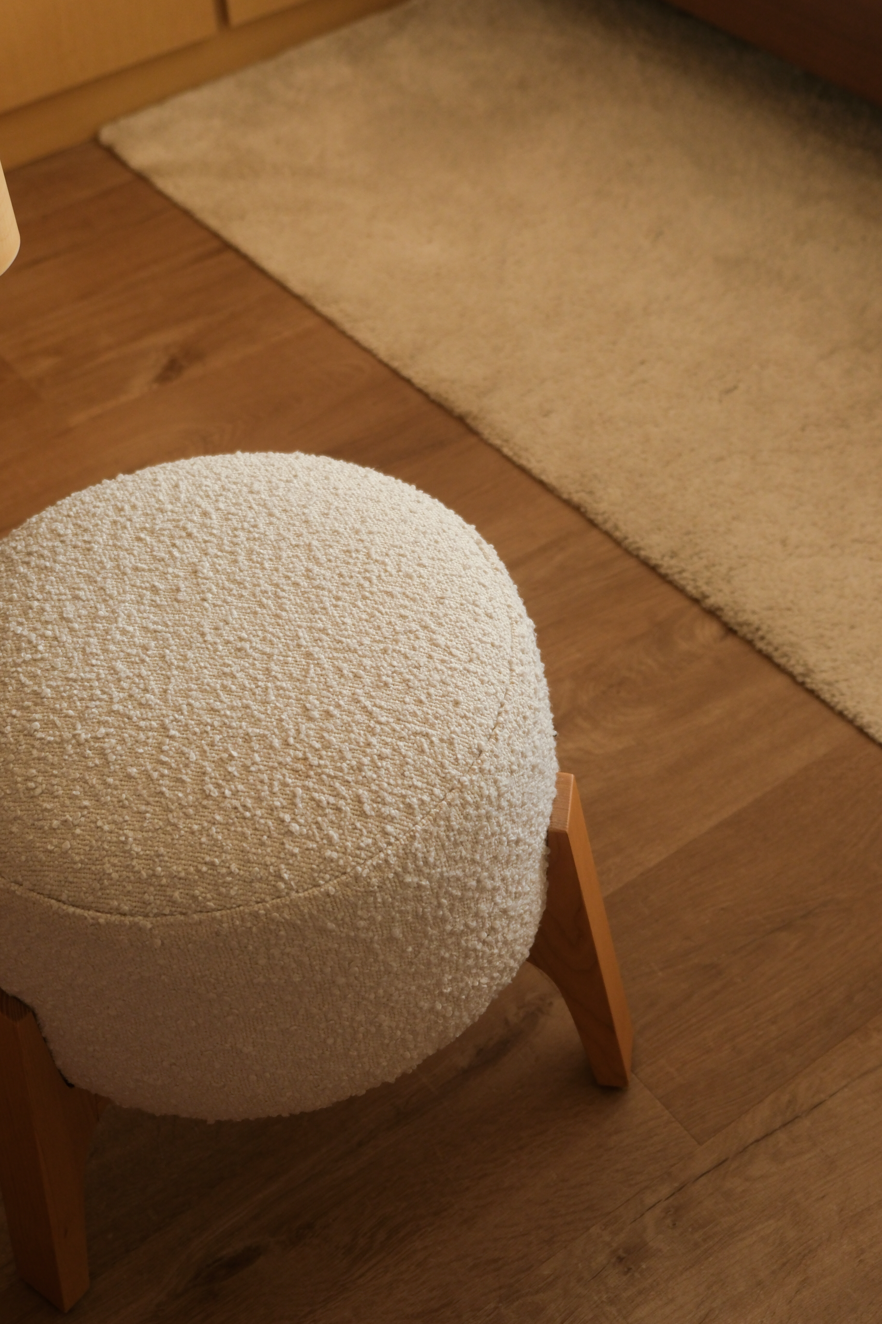 Minimalist Japandi Elegance. Warm tones and natural light.  - Round, cushioned, beige, textured, fluffy, wooden, stool