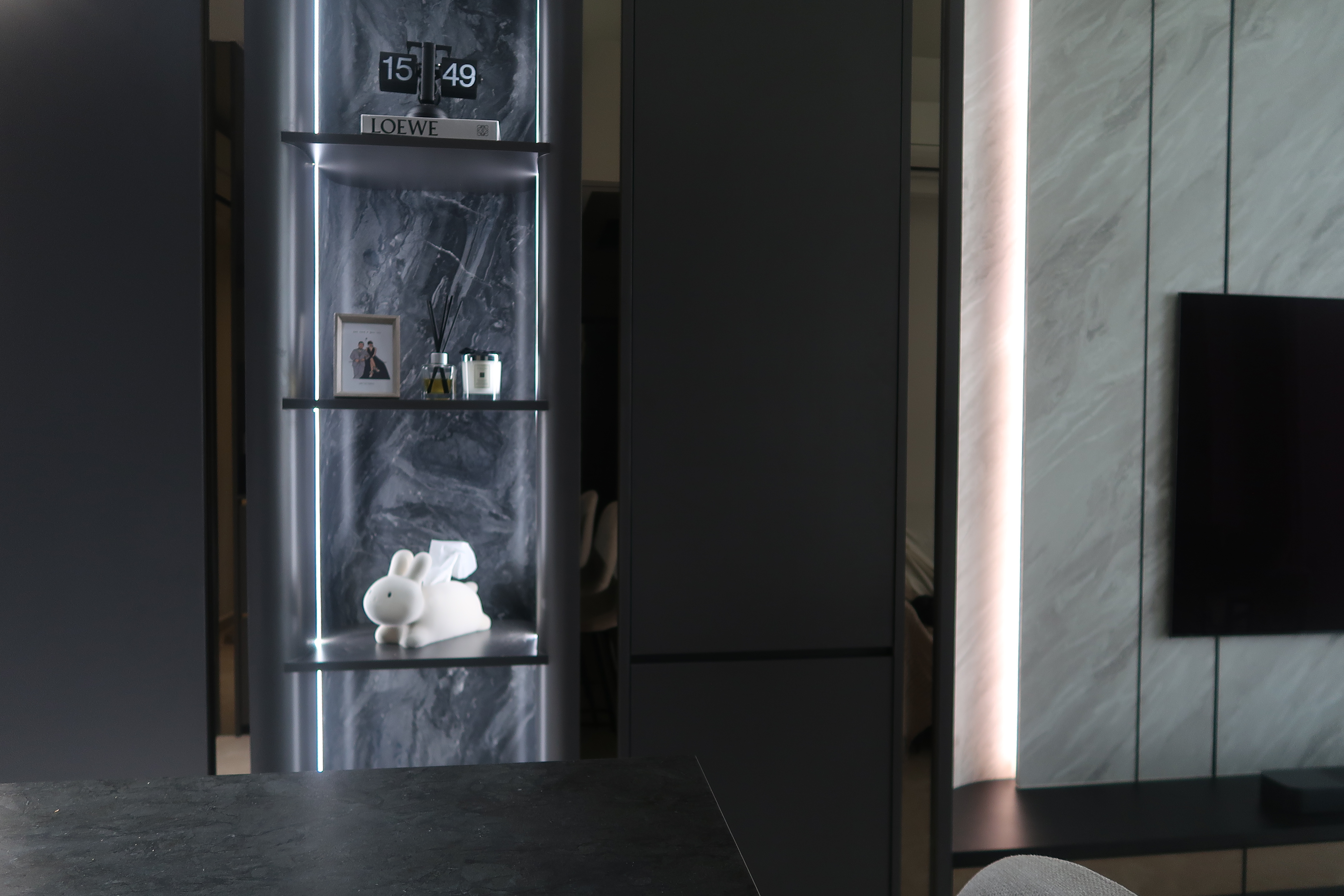 Simple and Sleek High Ceiling Living Room: Modern Dark Loft at North - Shelf with framed photo, candles, and a rabbit