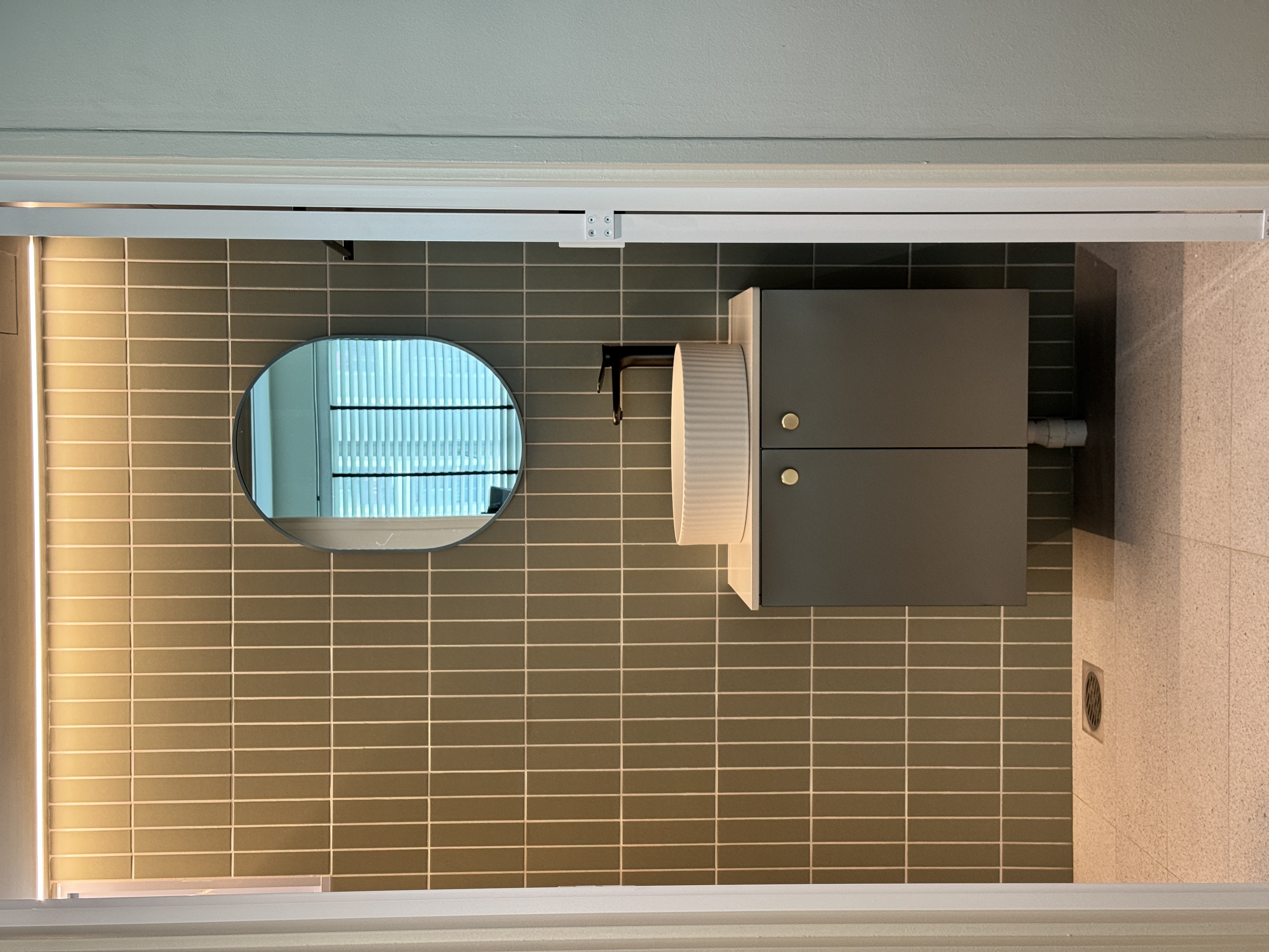 🏡🚻 Shower Screen: Yay or Nay?  - Modern bathroom interior, tiled floor, circular mirror, gray cabinets, white countertop