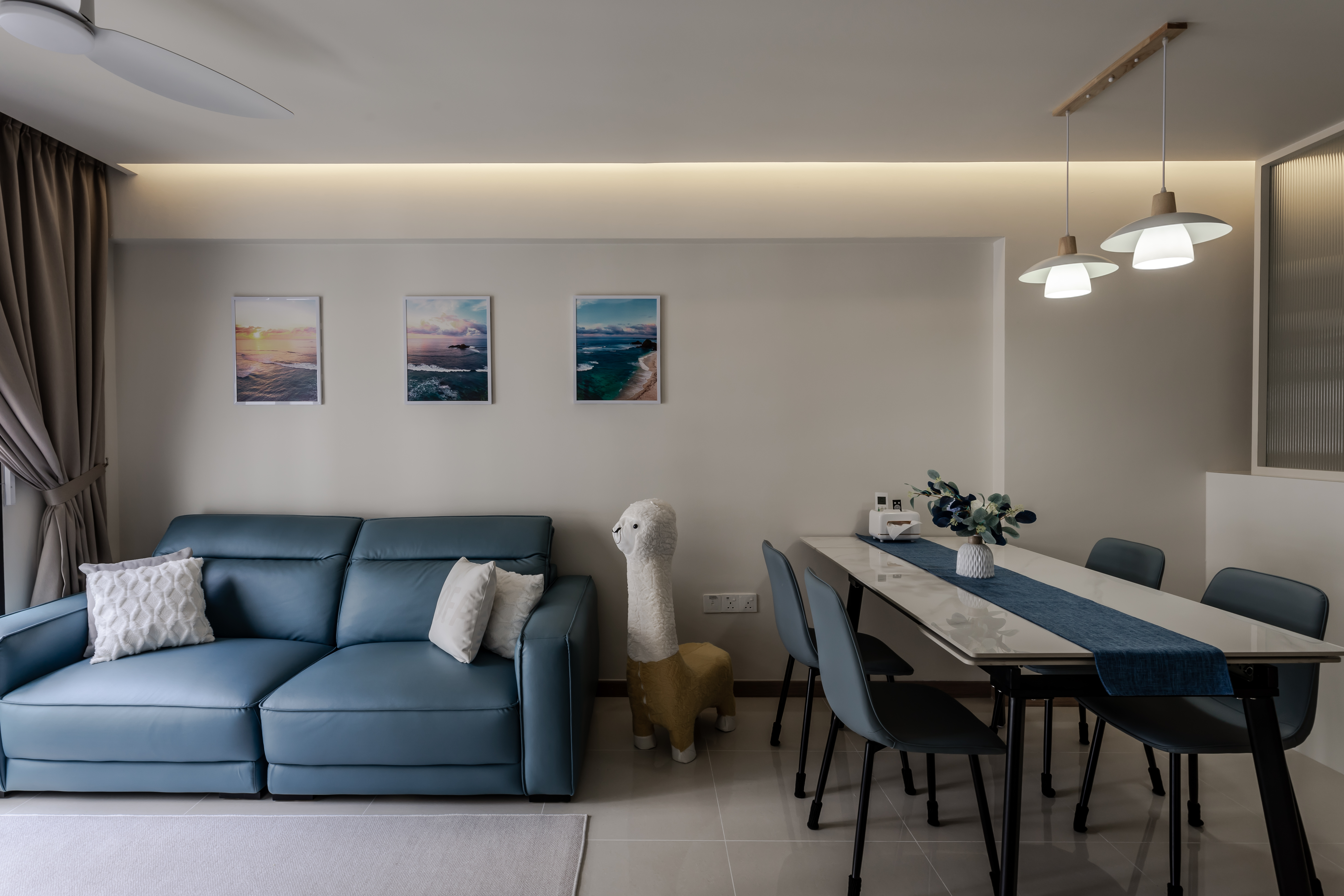 A cosy coastal kid-friendly haven  - Modern living room with blue leather sofa, white and yellow llama sculpture, dining