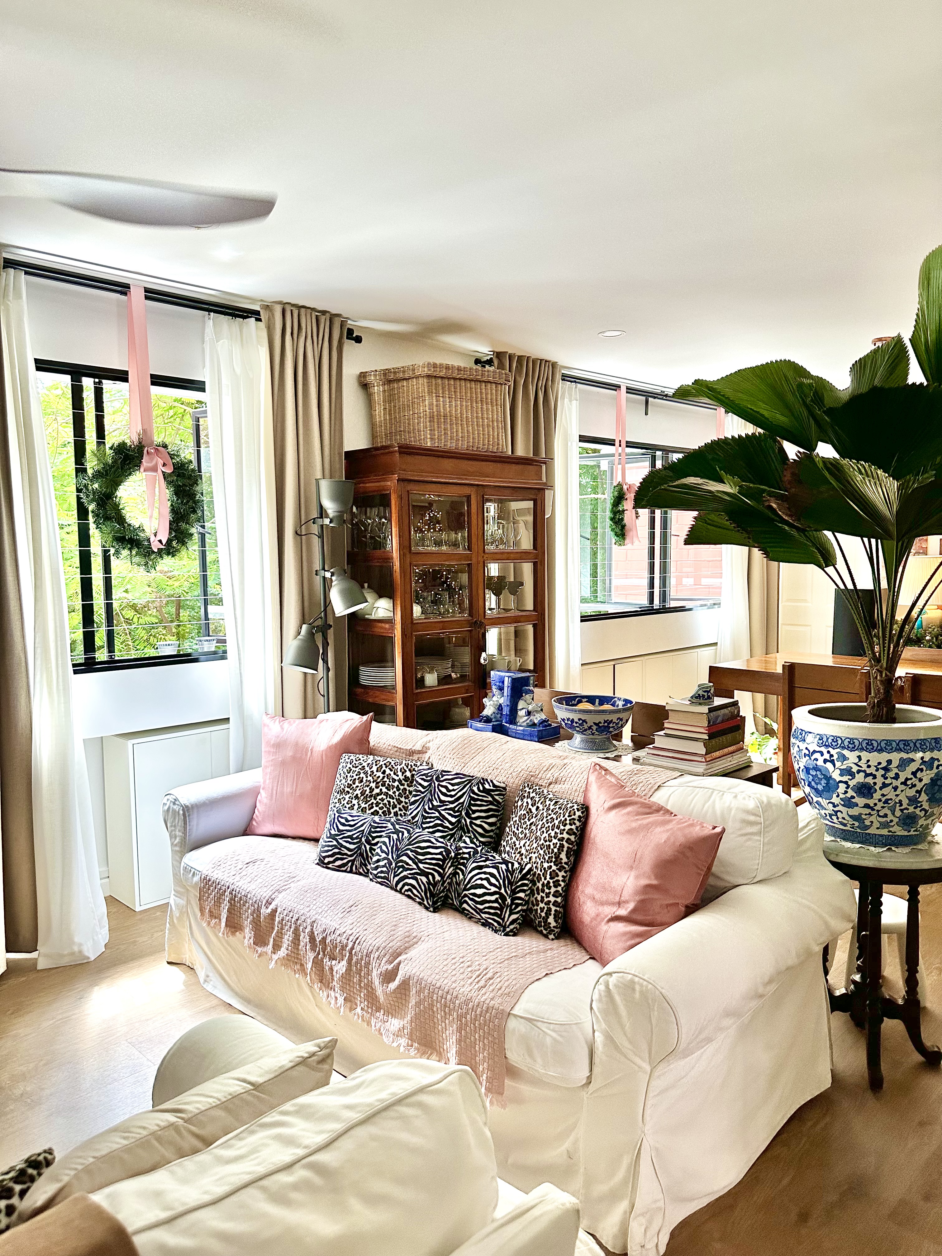 From Drab to Fab: Our Living Room Transformation  - White and beige sofa, pink and zebra patterned pillows, wooden cabinet