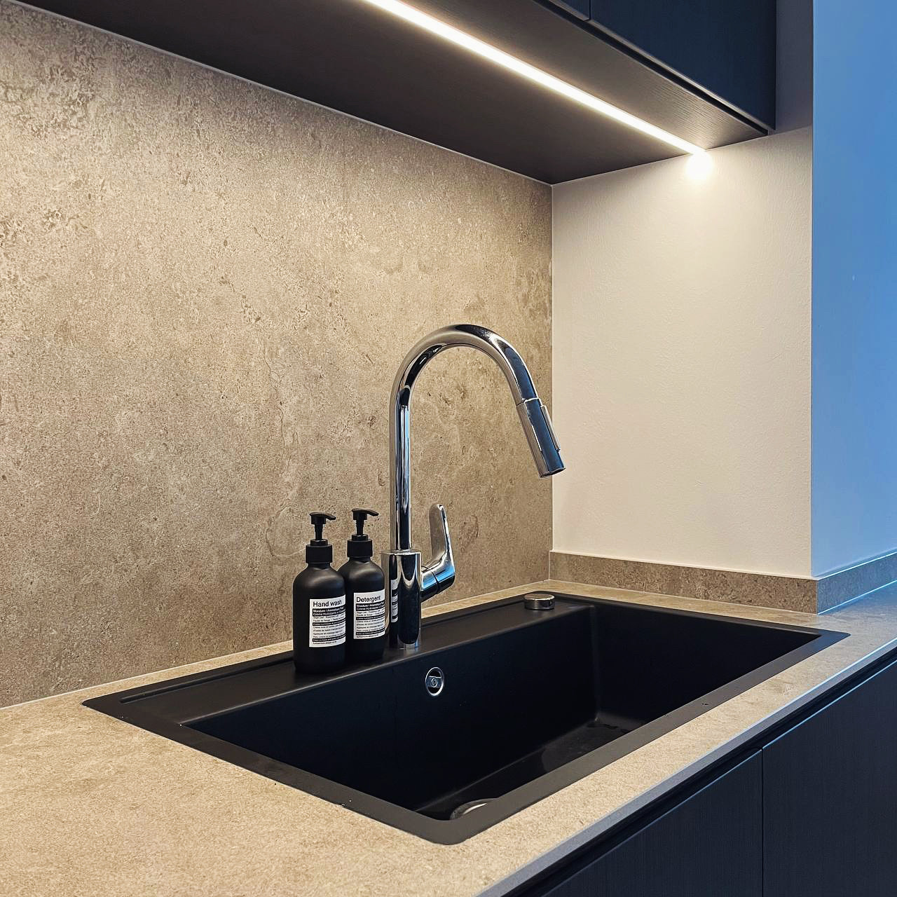 Kitchen: Dark But Functional - Modern kitchen sink, sleek faucet, black and beige countertop, under-cabinet lighting, dual
