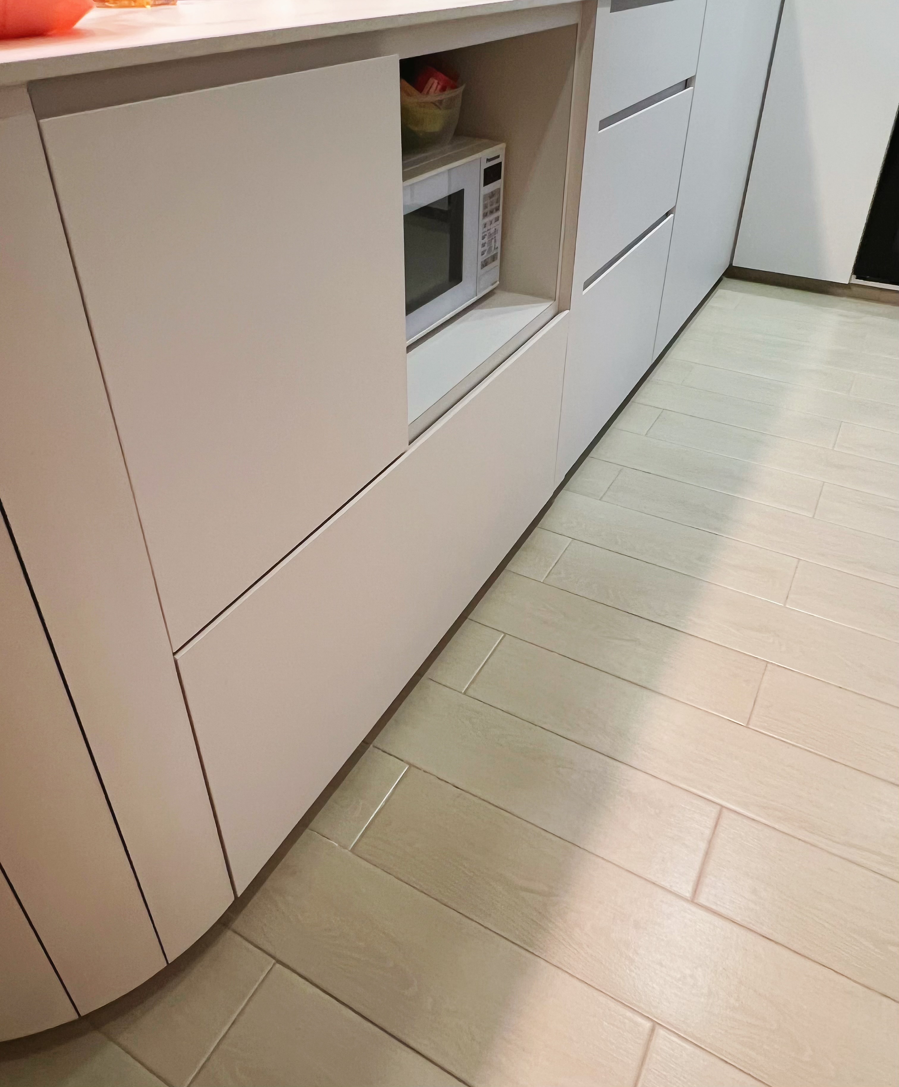 An all white kitchen separated  into wet and dry areas - White kitchen cabinets, light wooden floor, modern design