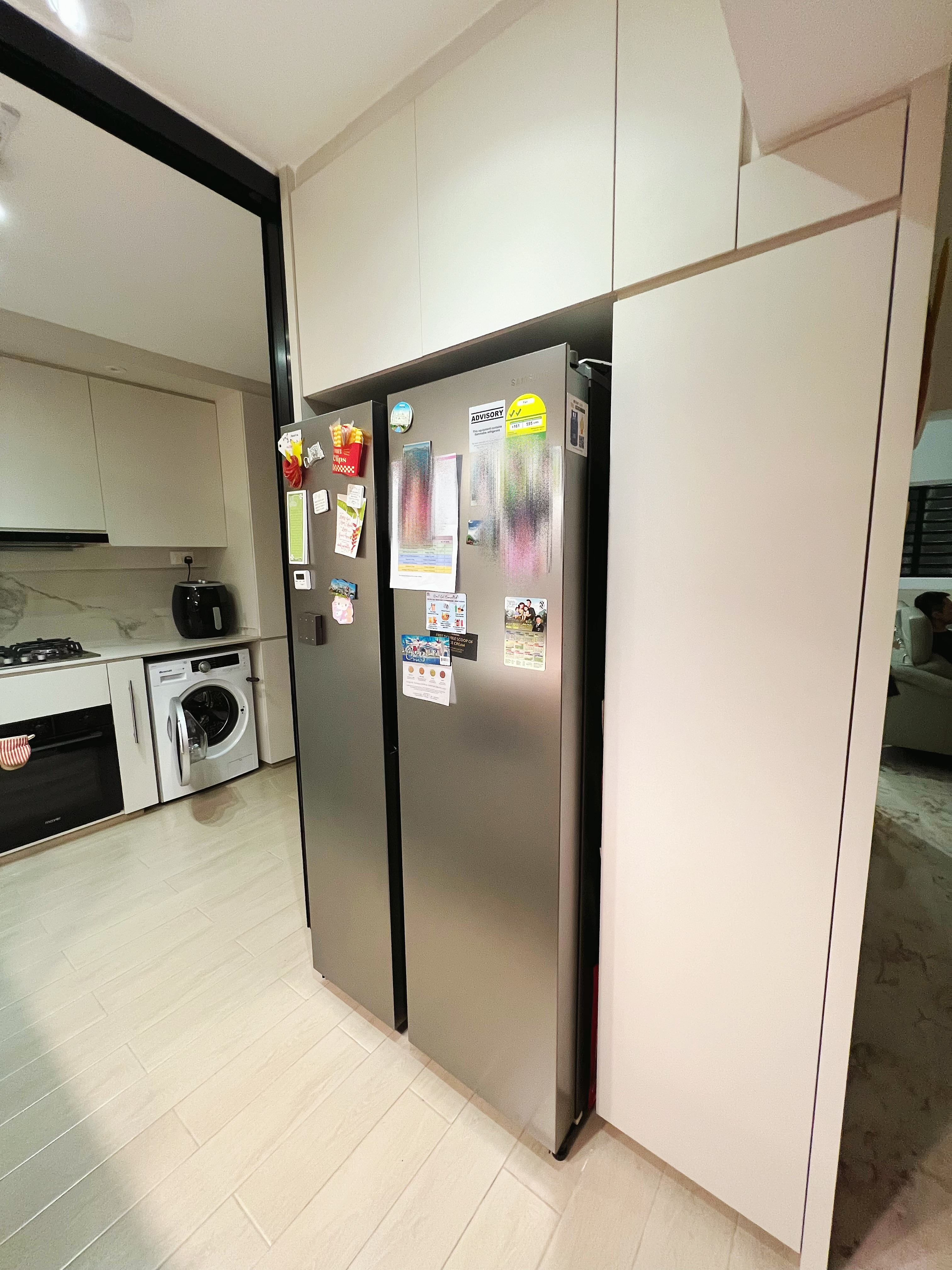 An all white kitchen separated  into wet and dry areas - Modern kitchen with stainless steel refrigerator, white cabinets