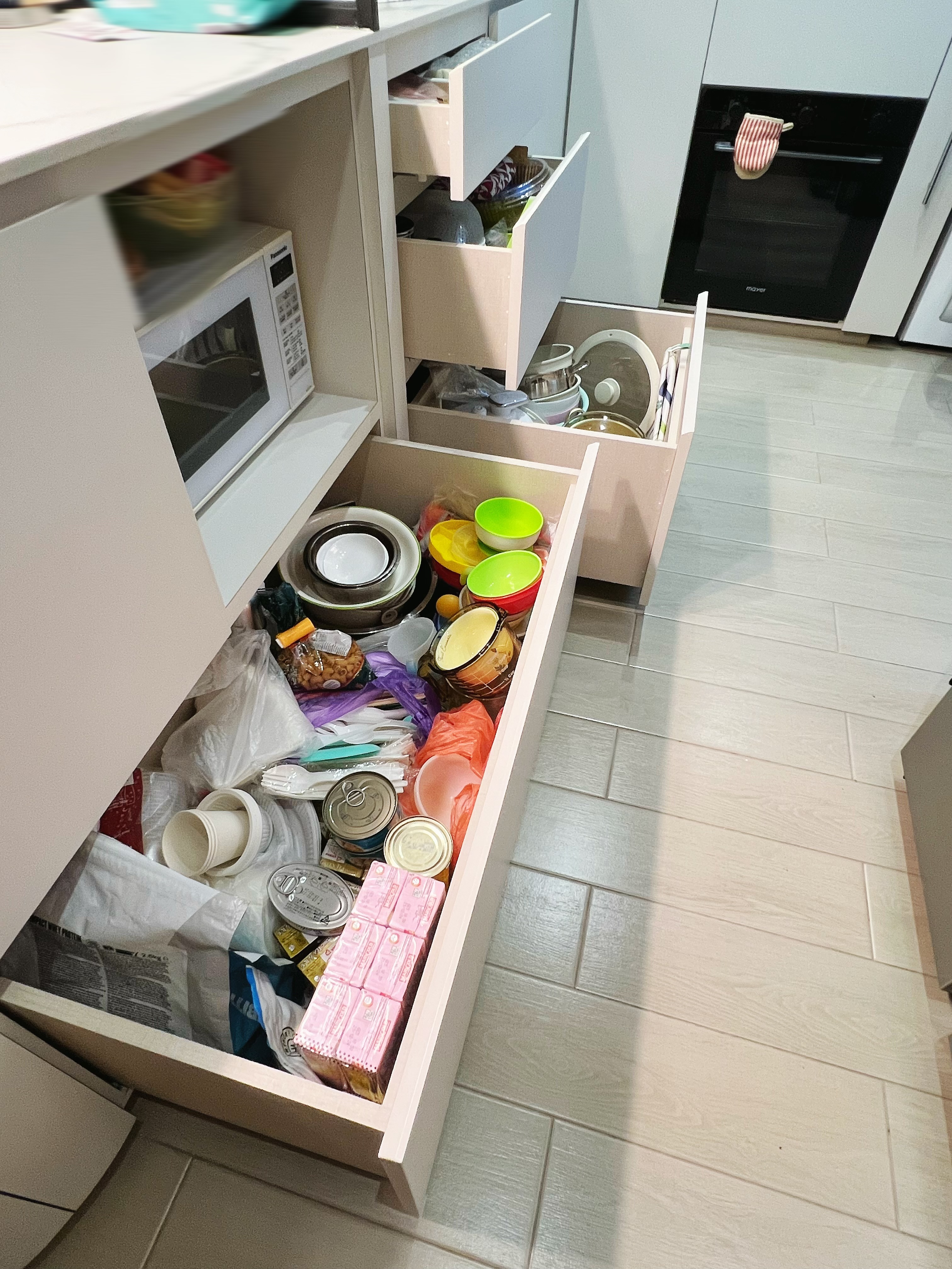 An all white kitchen separated  into wet and dry areas - microwave, kitchen drawer, cluttered pantry, white cabinets, open