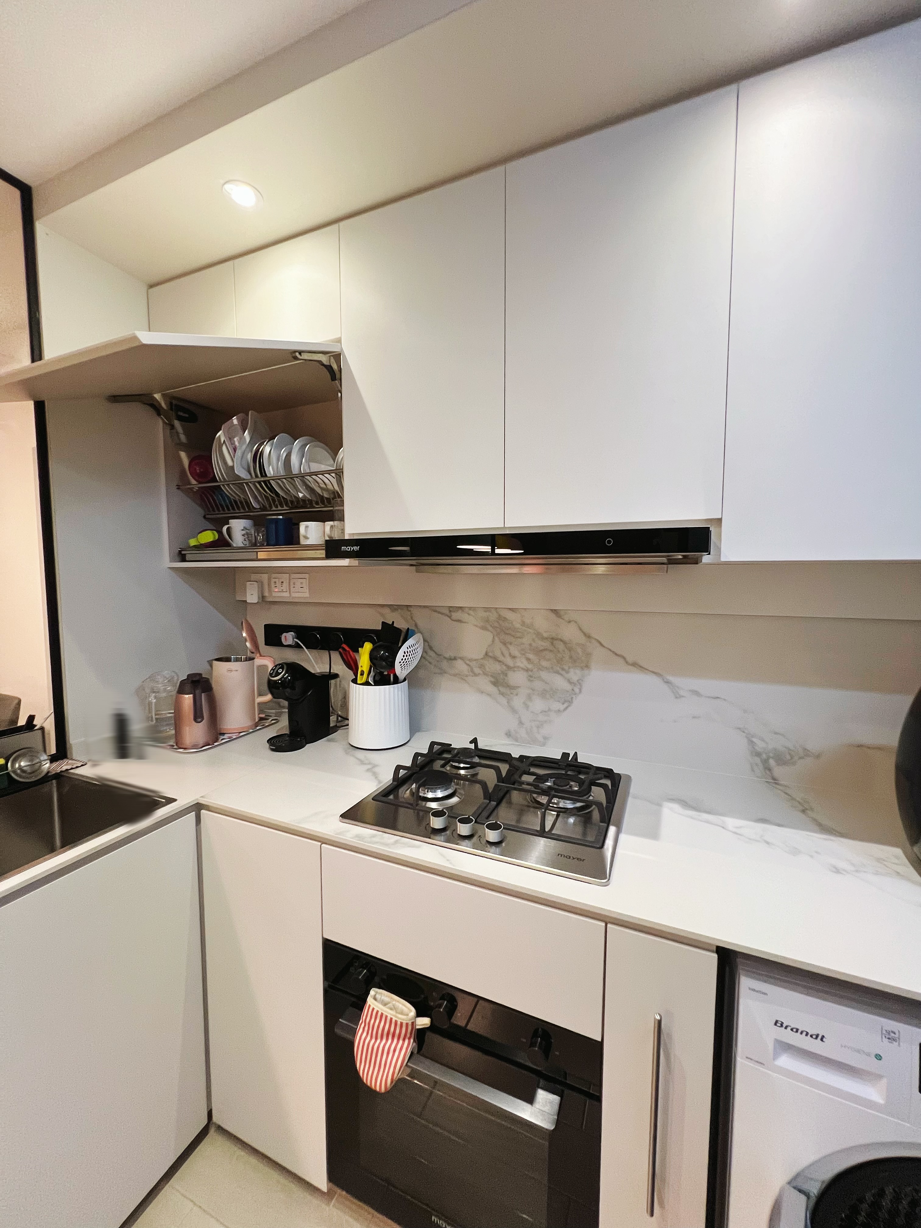 An all white kitchen separated  into wet and dry areas - White kitchen cabinetry, stainless steel stove, black range hood