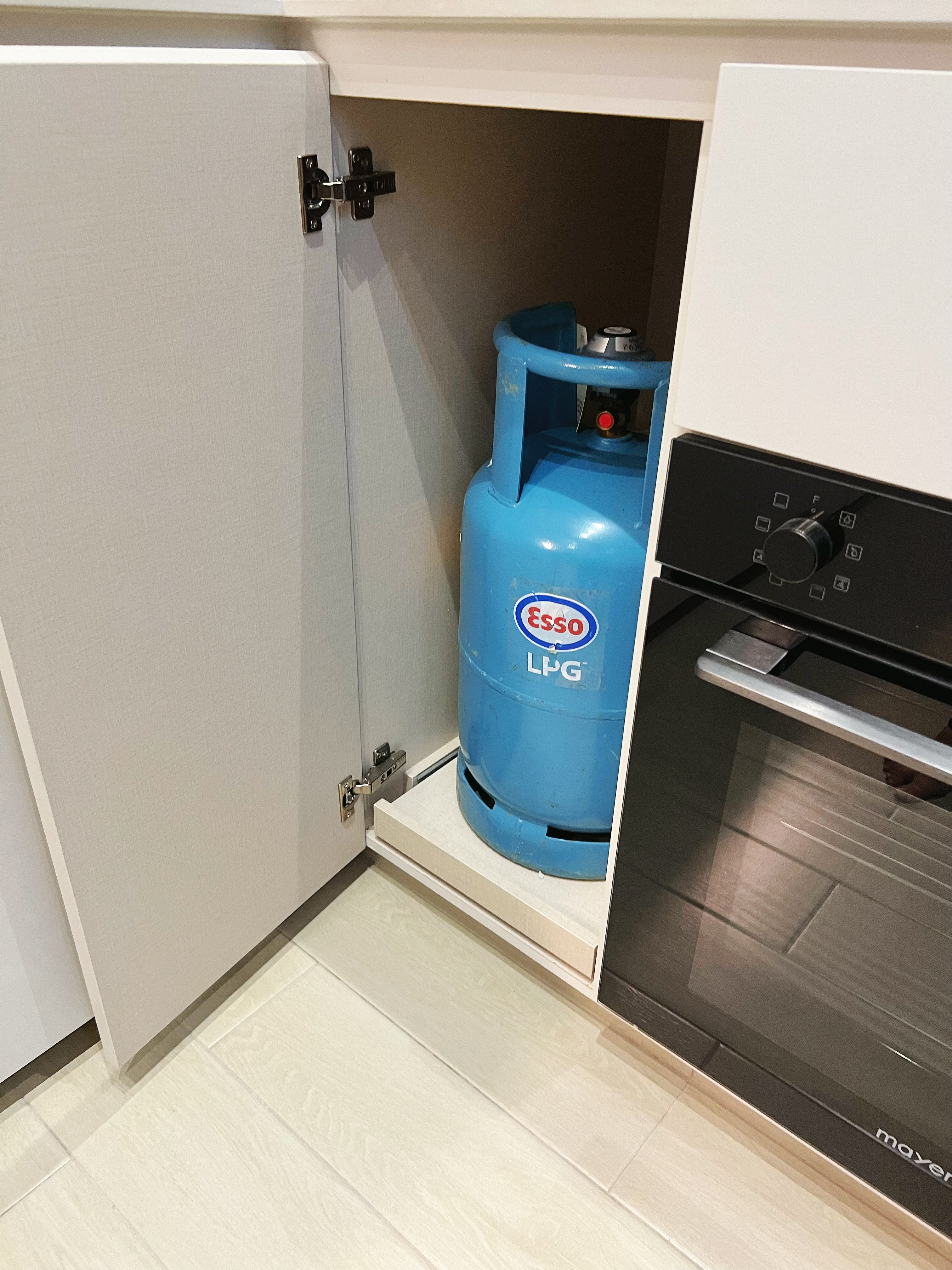 An all white kitchen separated  into wet and dry areas - blue gas cylinder, kitchen cabinet, LPG gas tank, modern kitchen