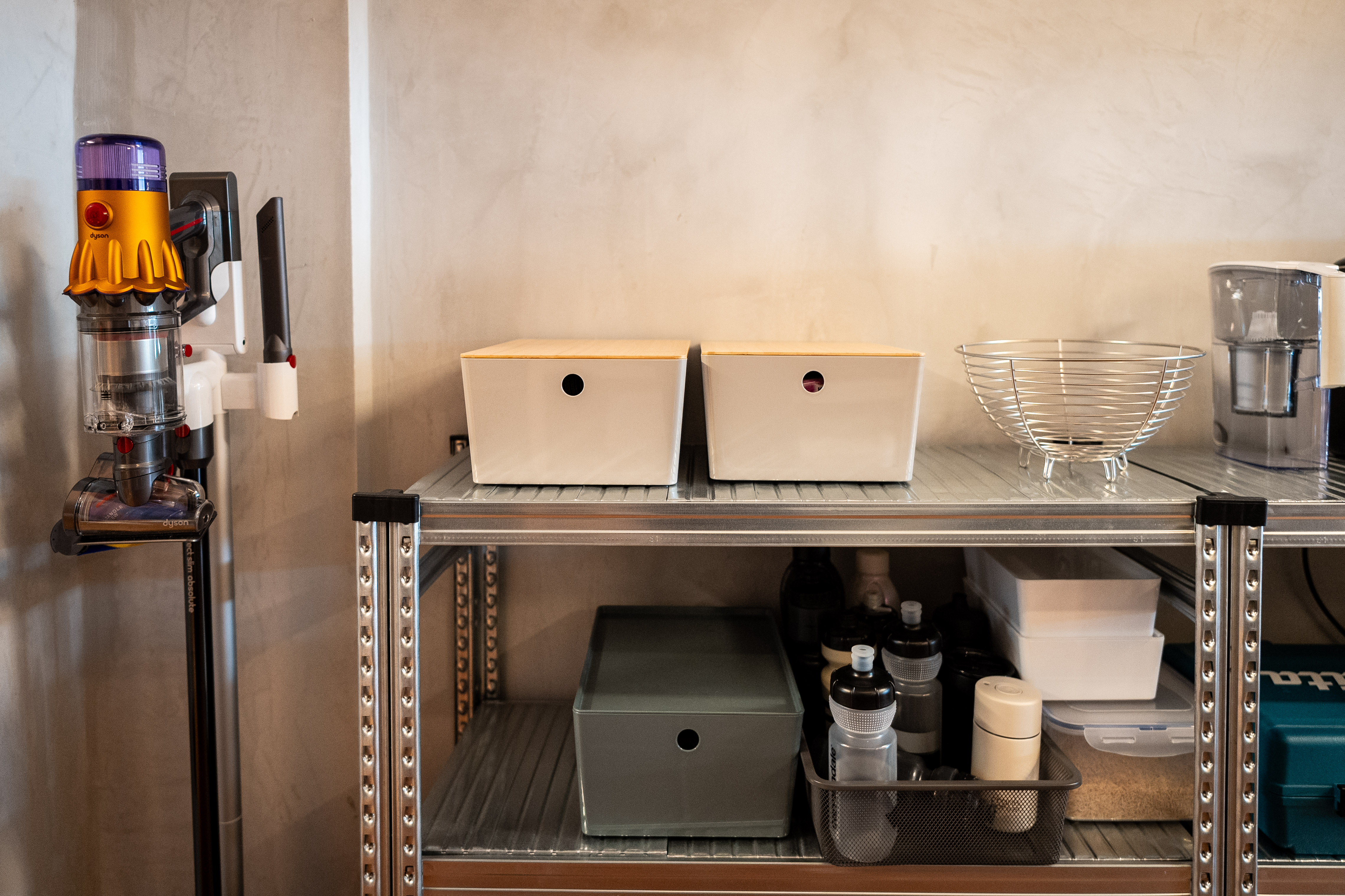 A Coffee Lover's Spacious & Charming Kitchen - Vacuum cleaner on wall, metal shelf, two white boxes, glass bowl, metal rack