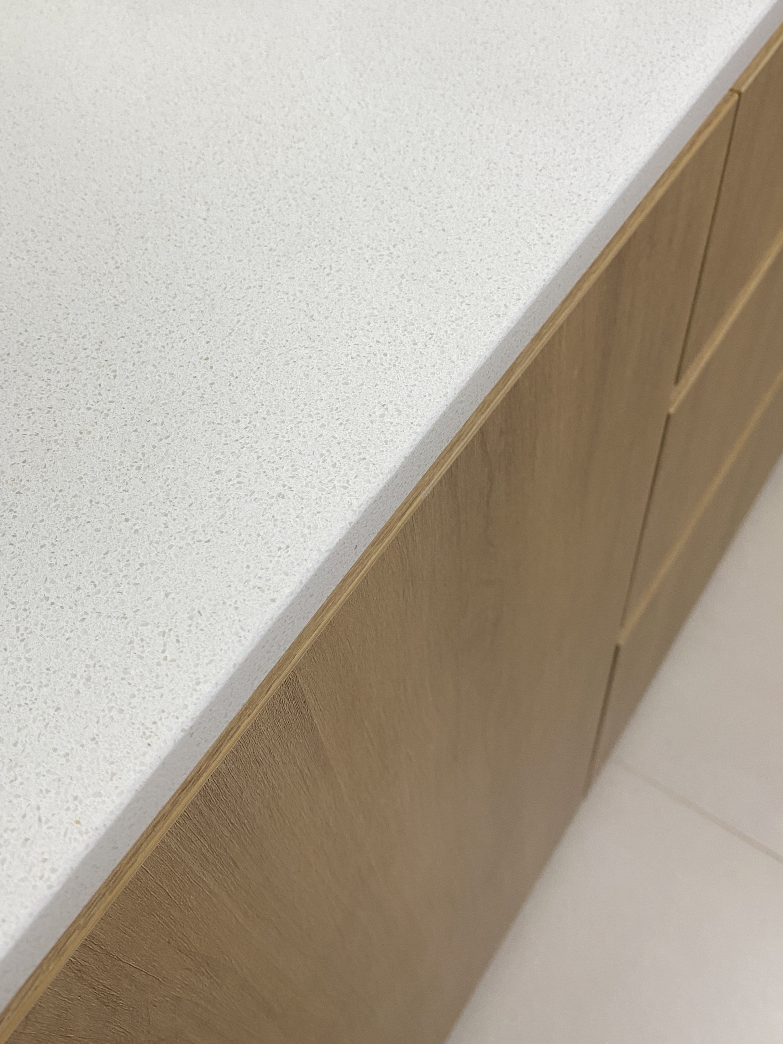 Kitchen: Multifunctional Space Combining Laundry and Cooking Area - White speckled countertop, light wood cabinets, corner