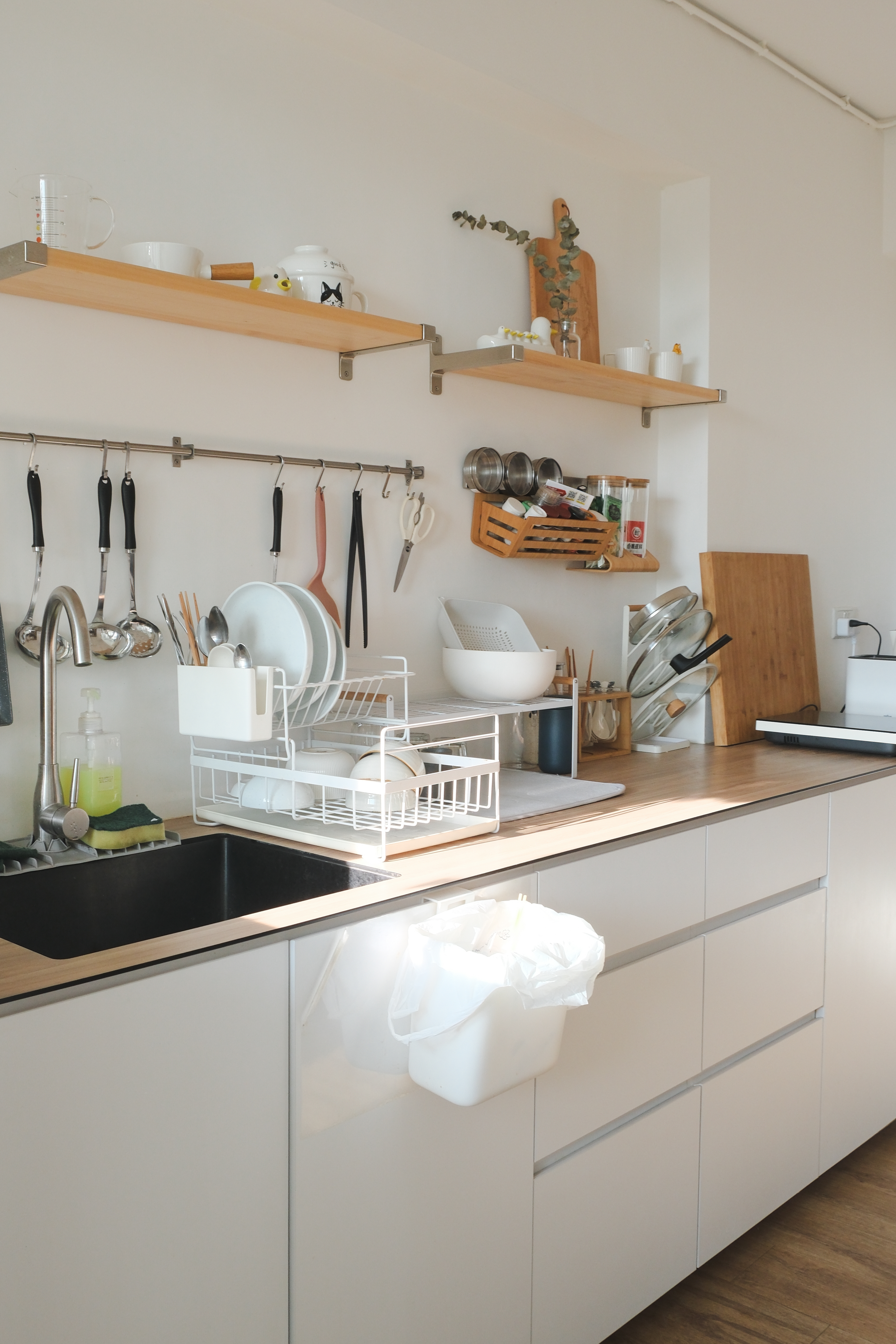 Clean and Functional: A Kitchen Designed with Smart Storage Solutions - kitchen sink, white dish rack, wooden shelf