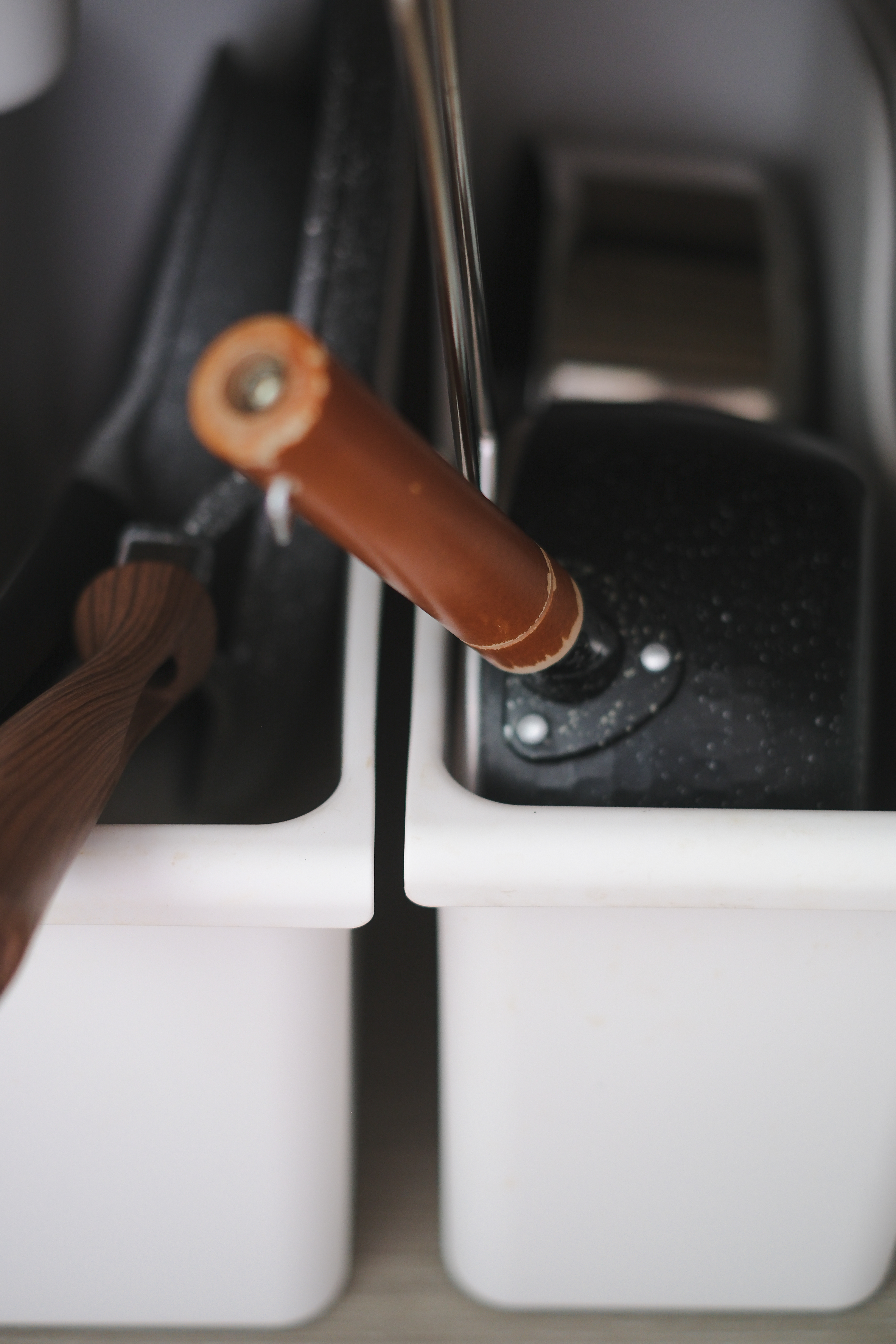 Clean and Functional: A Kitchen Designed with Smart Storage Solutions - Wooden handle, stainless steel faucet, black sink