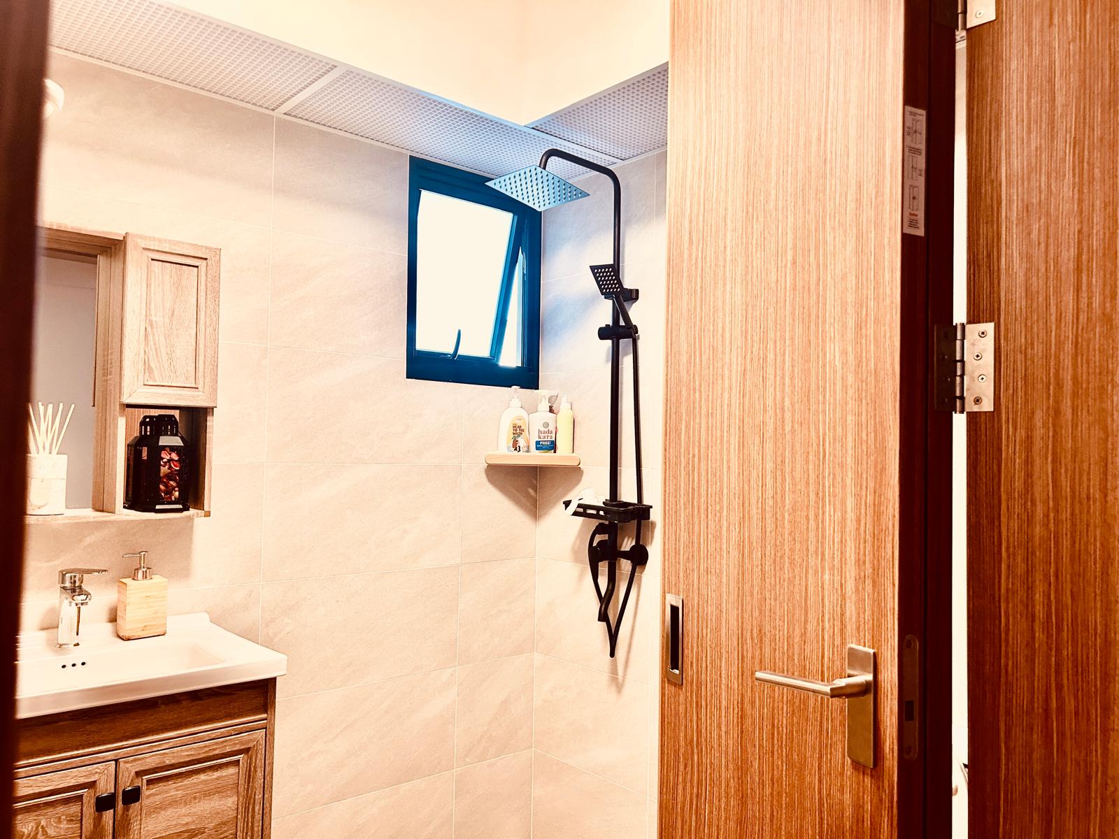 Airy and Inviting: A $26K Bohemian Mediterranean 4-RM BTO - Wooden bathroom vanity, beige tiled walls, black faucet, wooden