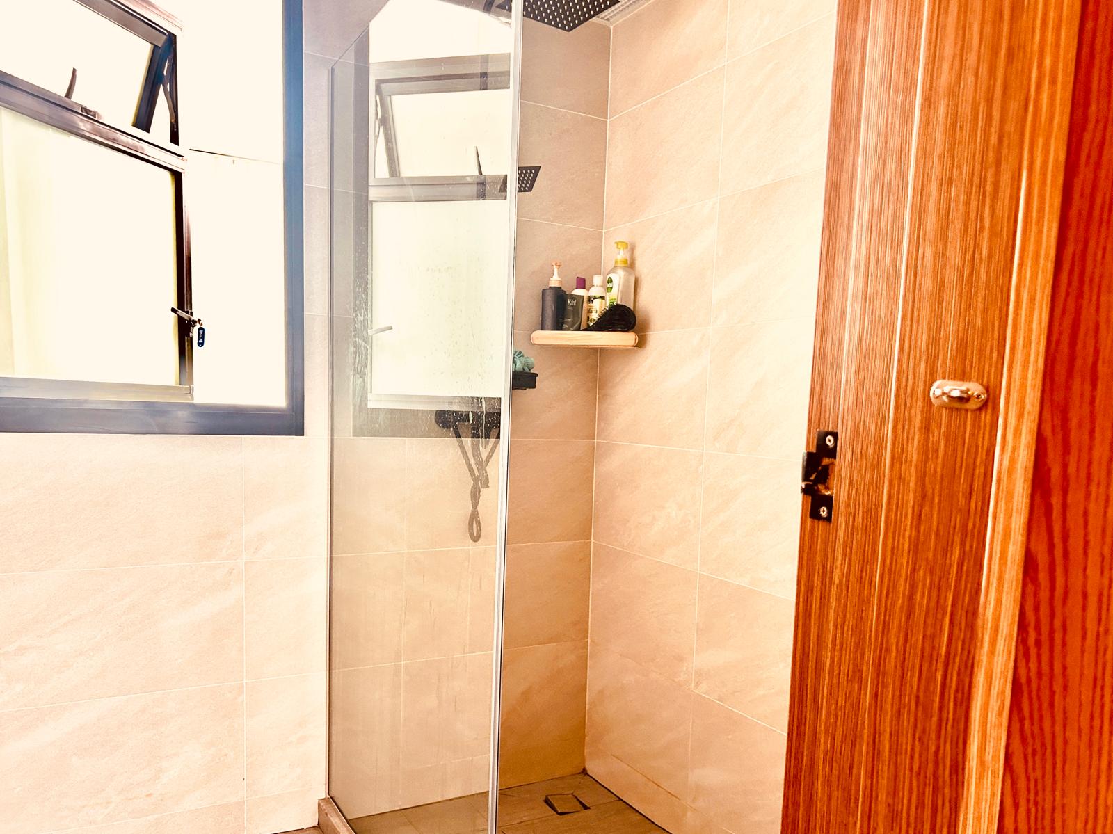 Airy and Inviting: A $26K Bohemian Mediterranean 4-RM BTO - Shower area with glass door, beige tiled walls, wooden door