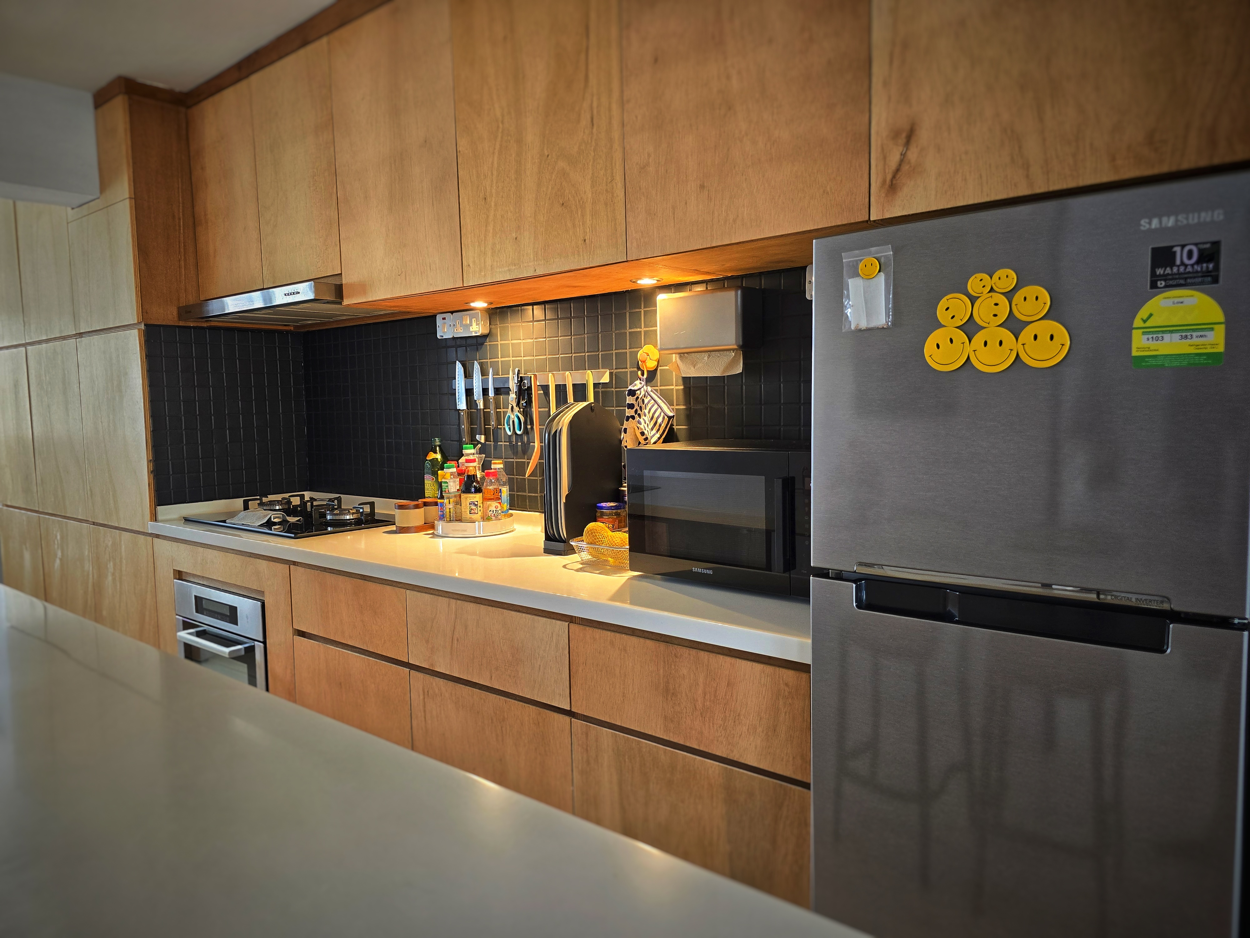 Our open kitchen concept - The plywood pantry. - Wooden cabinets, stainless steel refrigerator, black tiled backsplash