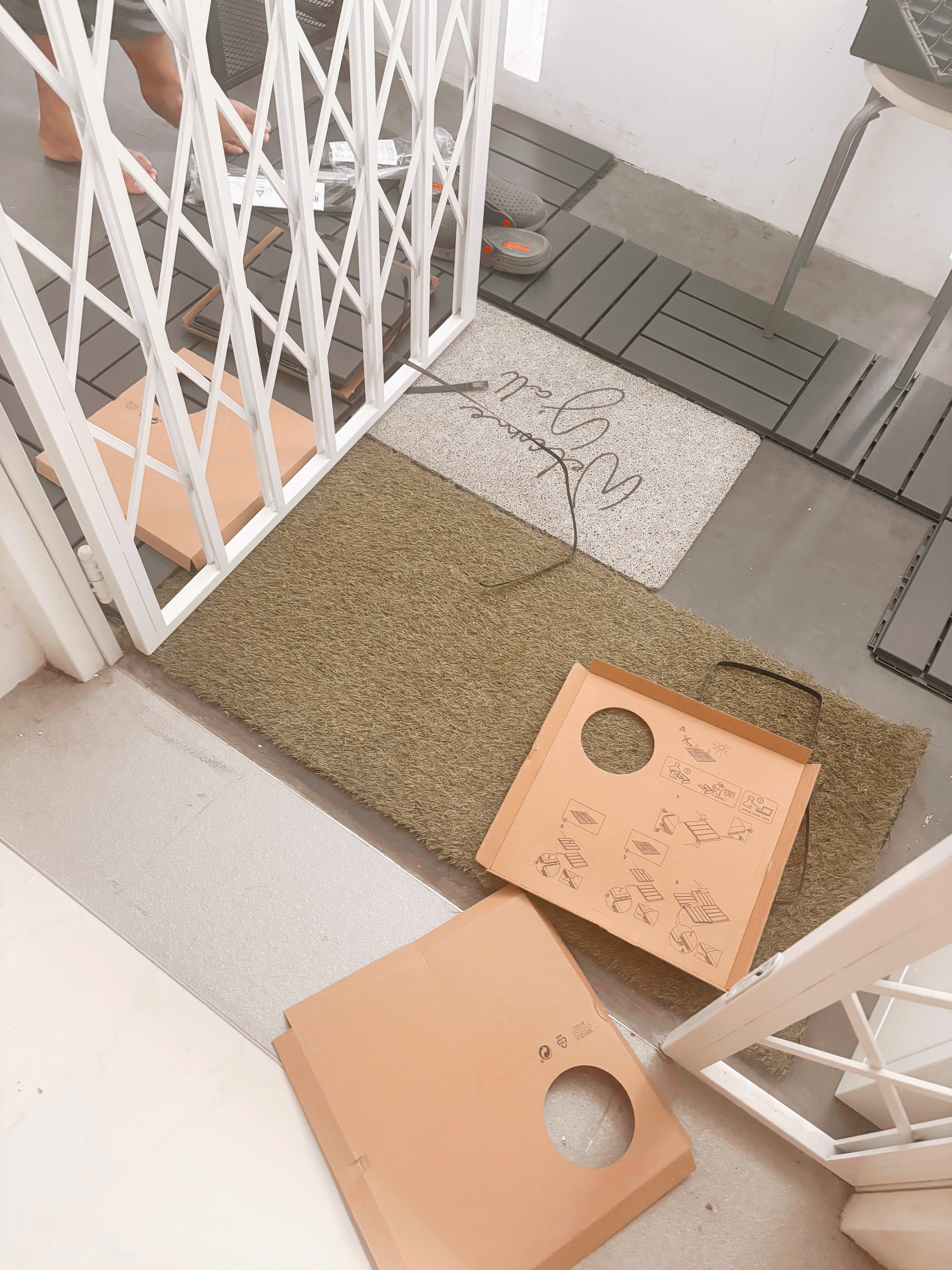 Entrance Glow-Up: Revamping Our Welcoming Space, One Detail at a Time! - White metal gate, gray slippers, cardboard package