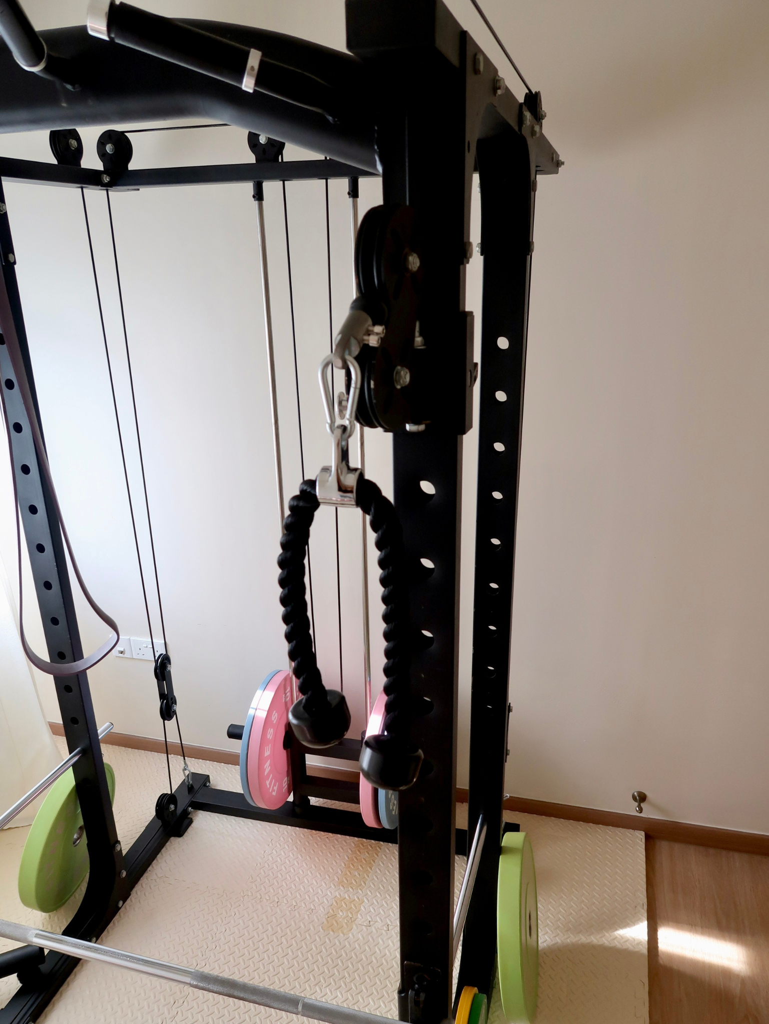 The Evolution Of My Home Gym From A Makeshift Kitchen - Black exercise machine, black metal frame, green weight plates, pink