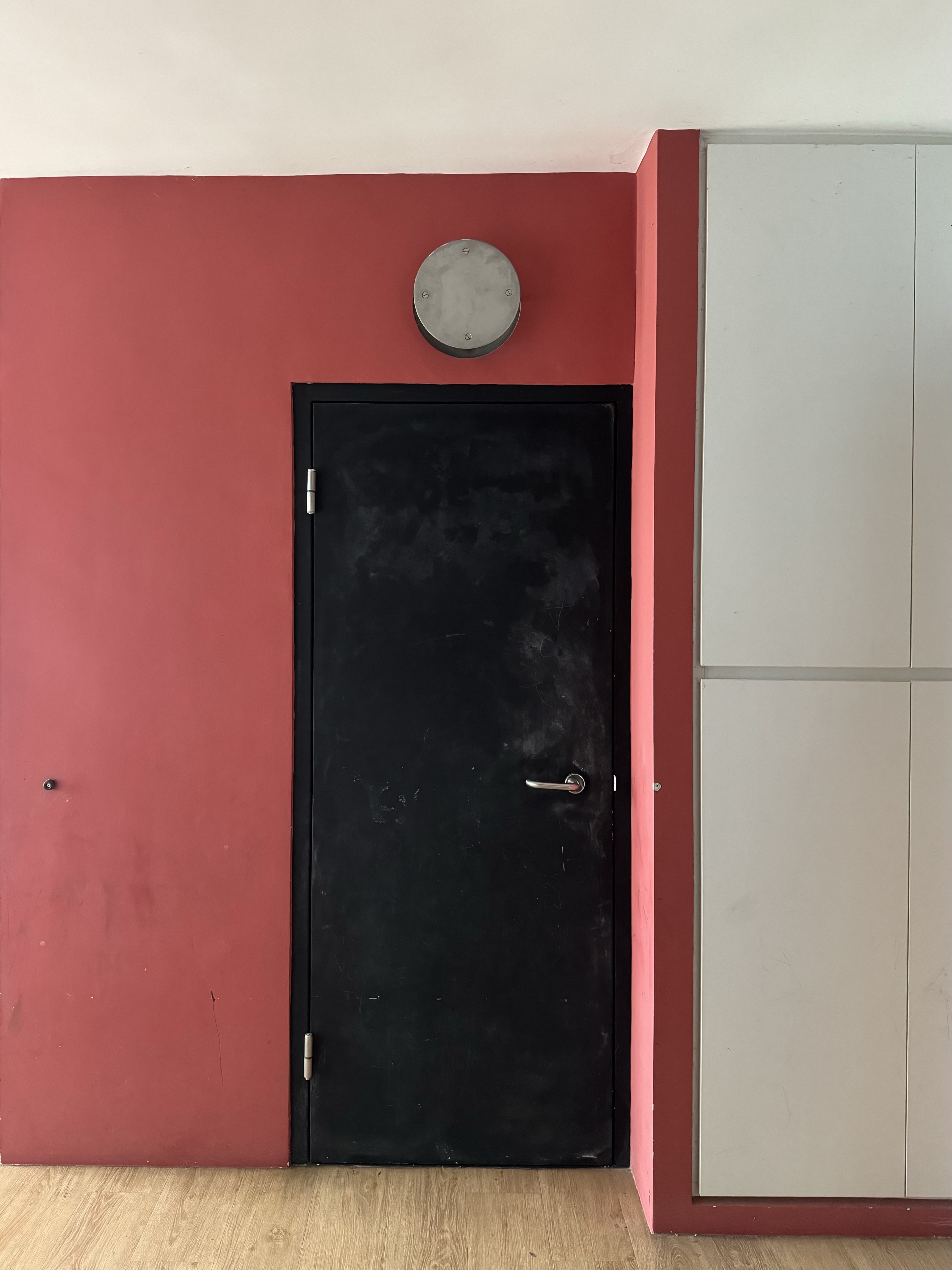Our Simple Entryway with No Built-Ins - Red wall, black door, circular clock, white cabinet, wooden floor, minimalistic