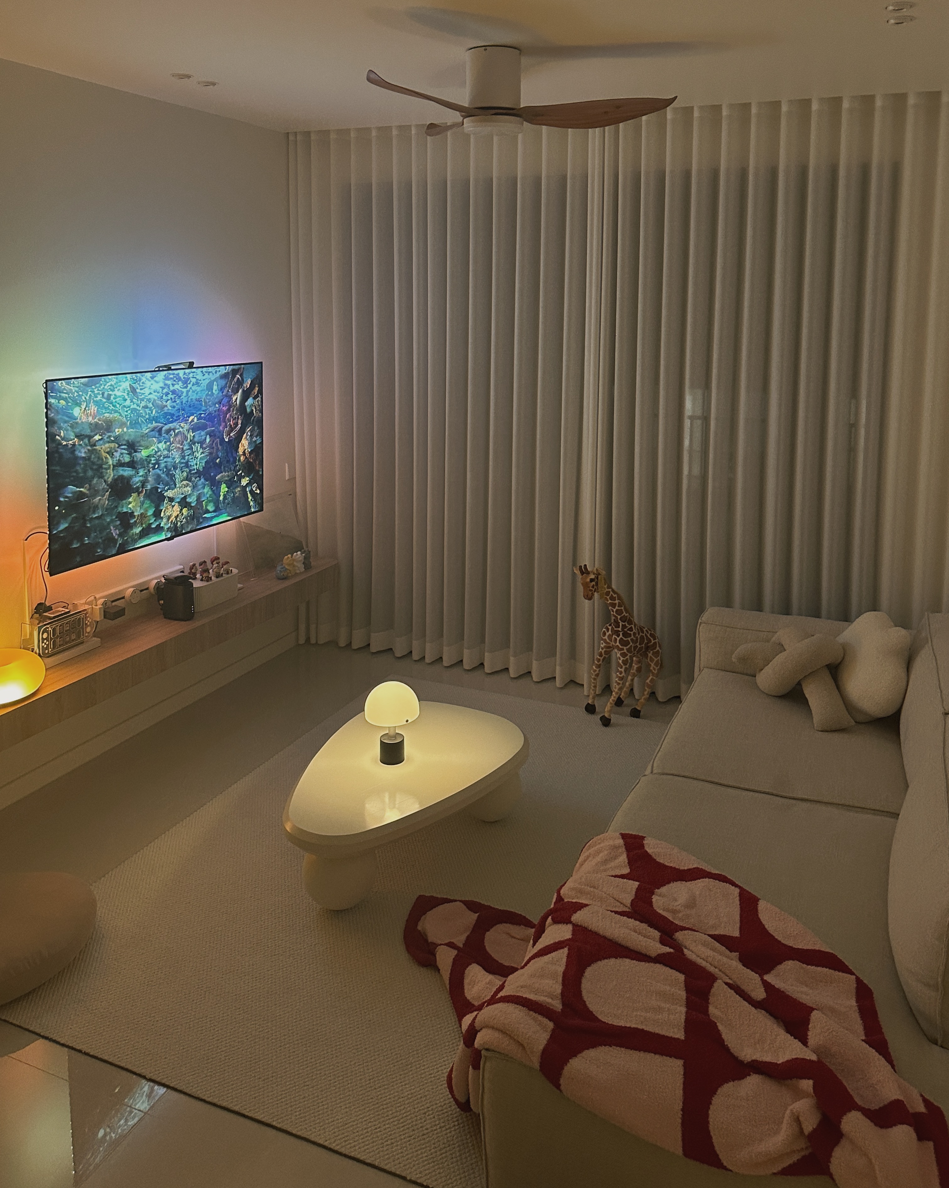 Inside a Warm Minimalist 3-Bedder Condo - Modern living room, cozy atmosphere, large flat-screen TV, aquarium display, soft