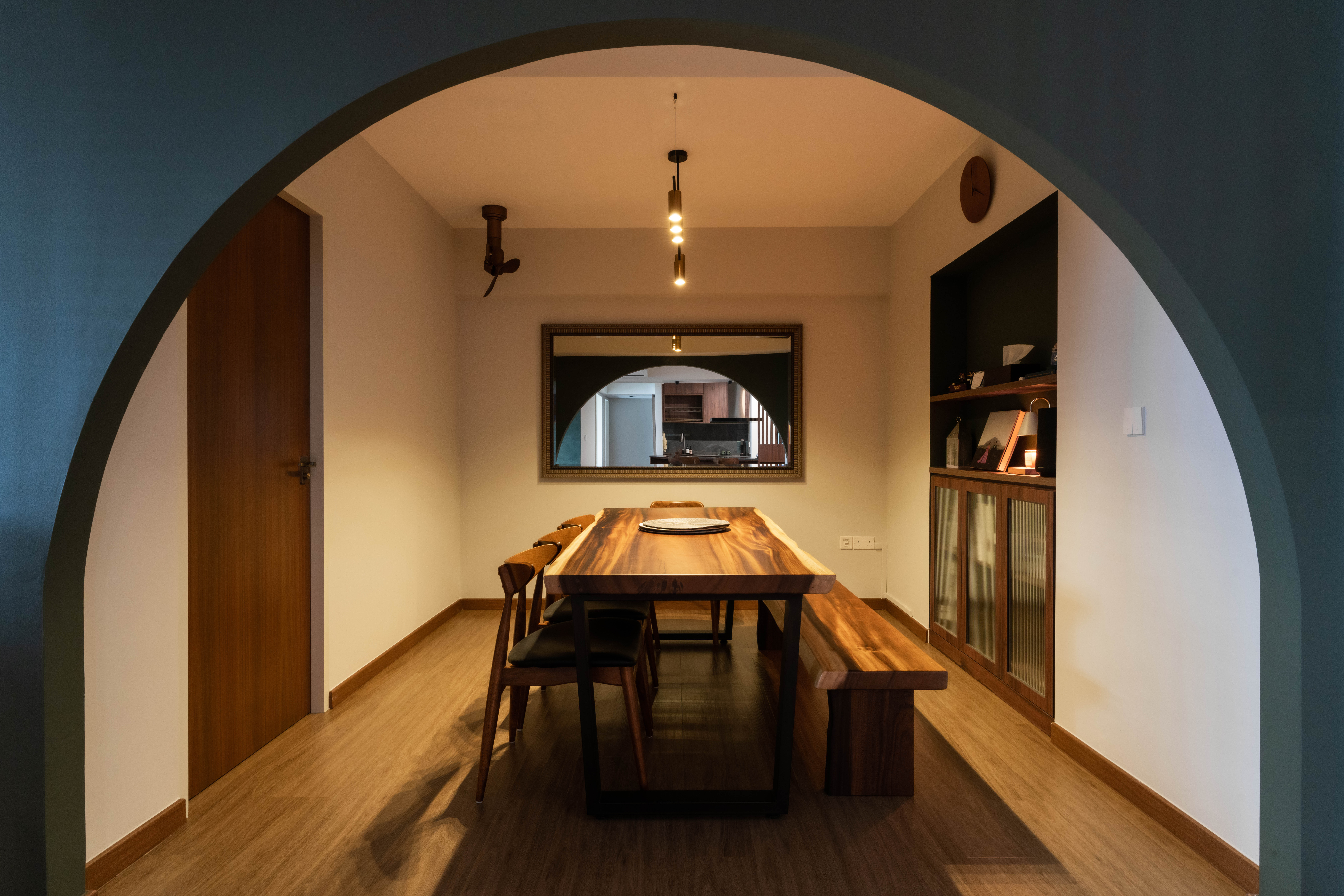Banter and Bites - Modern dining room with wooden furniture, minimalist design, warm lighting, large mirror, arched doorway
