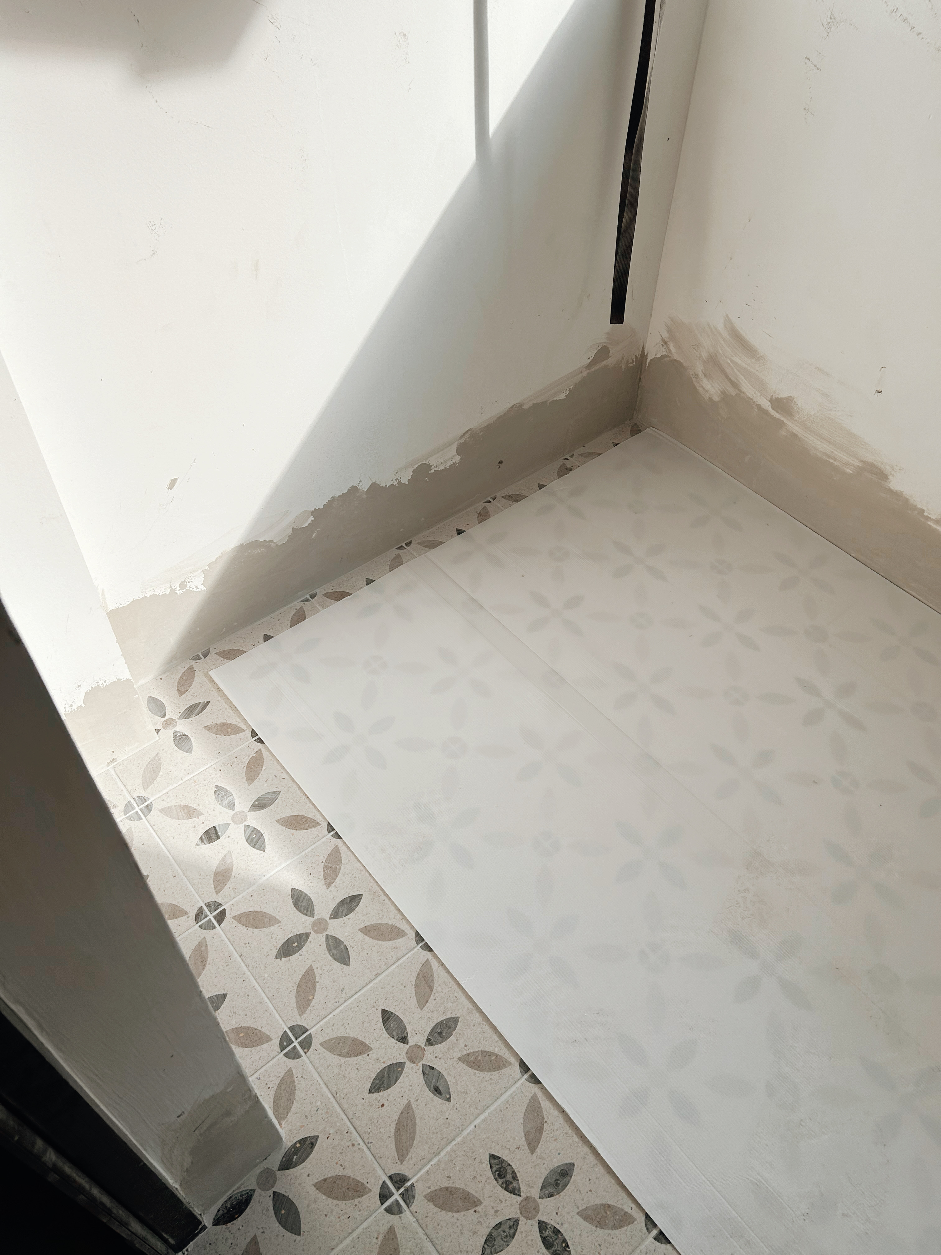 Tile Your Way to a Stunning Renovation: Tips from Loafy.Haus - White tiled floor with floral pattern, partially unfinished